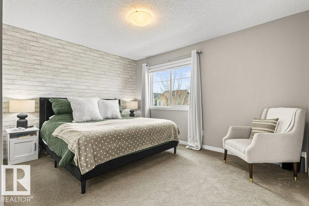 Carpeted bedroom featuring an accent wall and a textured ceiling - 3351 Orchards Link, Edmonton, AB - Indoor Photo Showing Bedroom