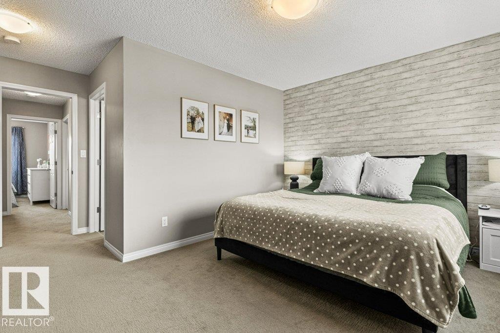 Carpeted bedroom with a textured ceiling and an accent wall - 3351 Orchards Link, Edmonton, AB - Indoor Photo Showing Bedroom
