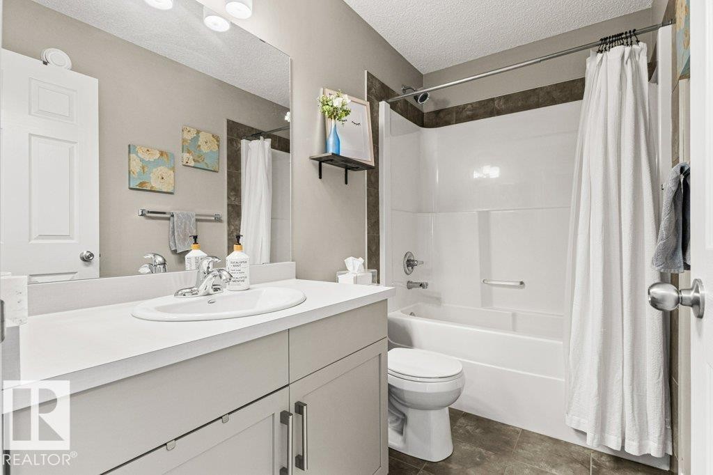Full bathroom featuring vanity, shower / bath combo with shower curtain, and a textured ceiling - 3351 Orchards Link, Edmonton, AB - Indoor Photo Showing Bathroom