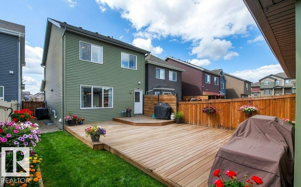 Back of property with a fenced backyard, a wooden deck, and a residential view - 3351 Orchards Link, Edmonton, AB - Outdoor With Deck Patio Veranda With Exterior