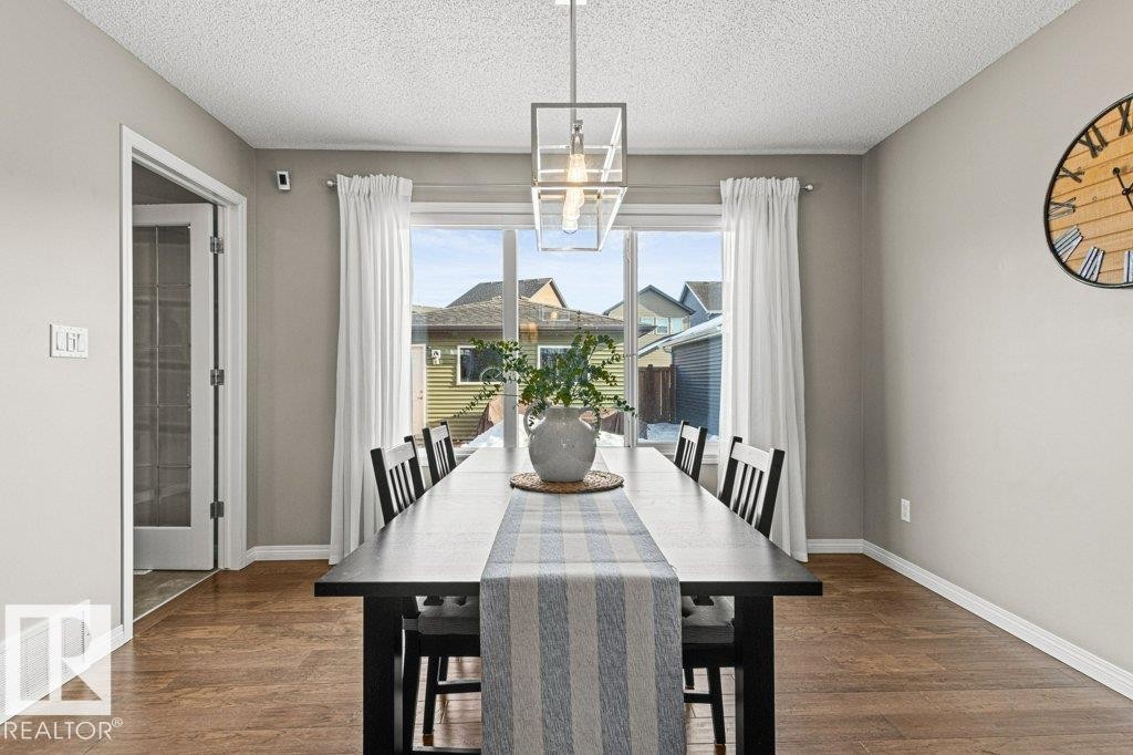 Dining space featuring dark wood finished floors, a chandelier, and a textured ceiling - 3351 Orchards Link, Edmonton, AB - Indoor Photo Showing Dining Room