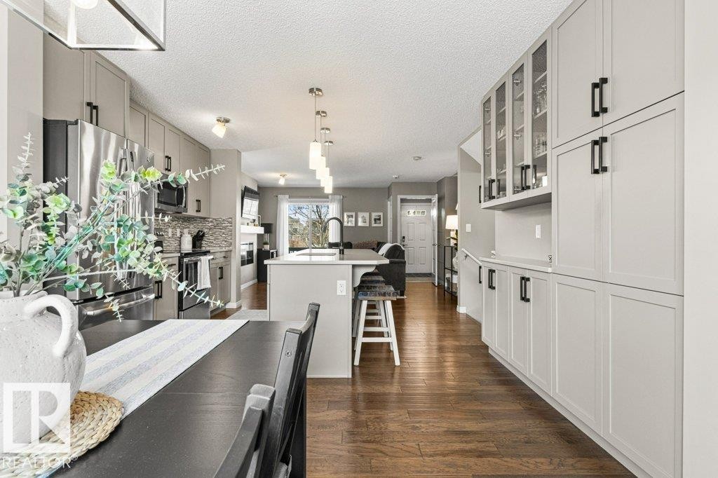 Dining area with dark wood-style floors, a textured ceiling, and a fireplace - 3351 Orchards Link, Edmonton, AB - Indoor Photo Showing Other Room