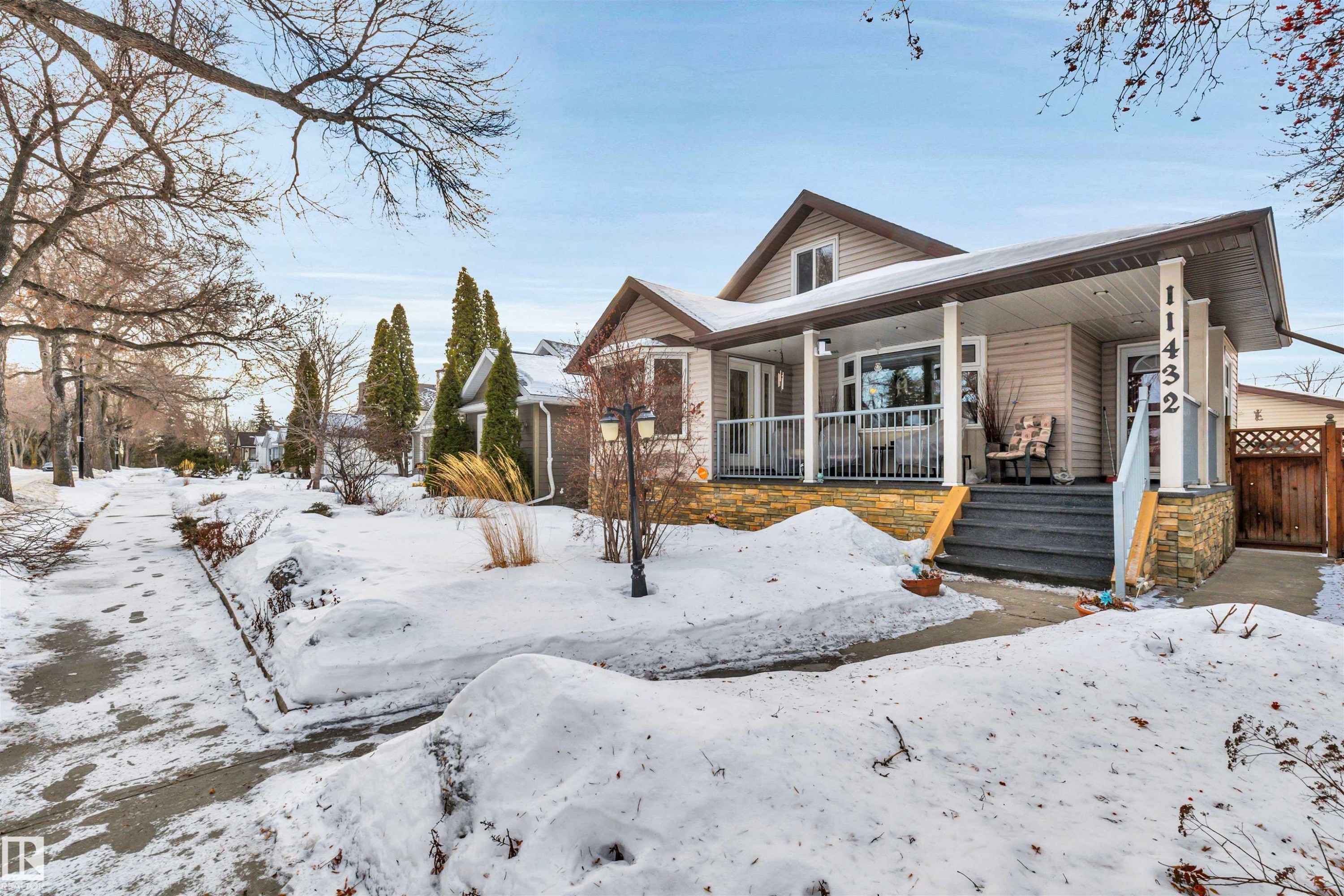 View of front of home featuring covered porch and stone siding - 11432 71 Street, Edmonton, AB - Outdoor With Deck Patio Veranda