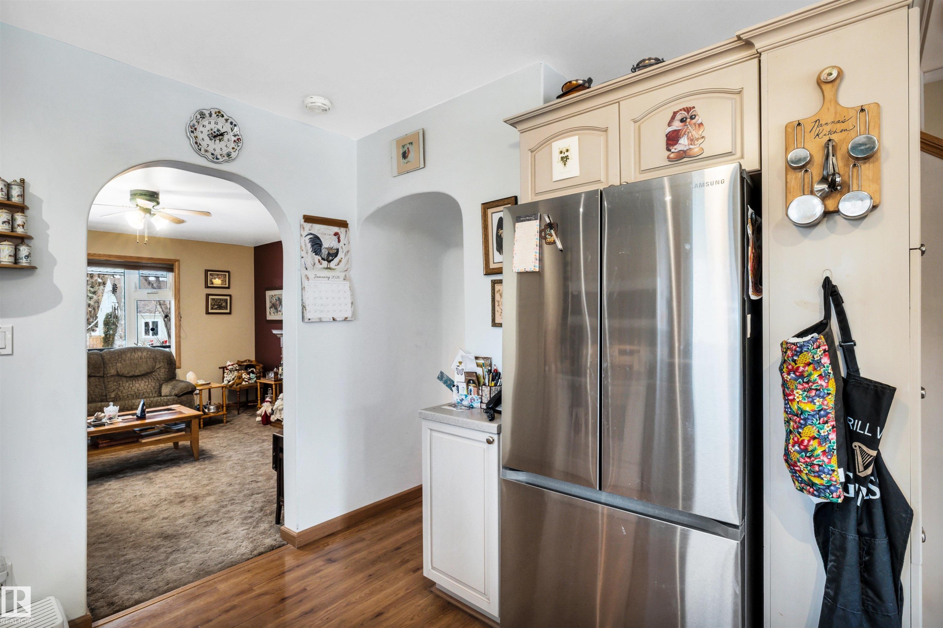 Kitchen featuring freestanding refrigerator, arched walkways, ceiling fan, dark wood-type flooring, and cream cabinetry - 11432 71 Street, Edmonton, AB - Indoor