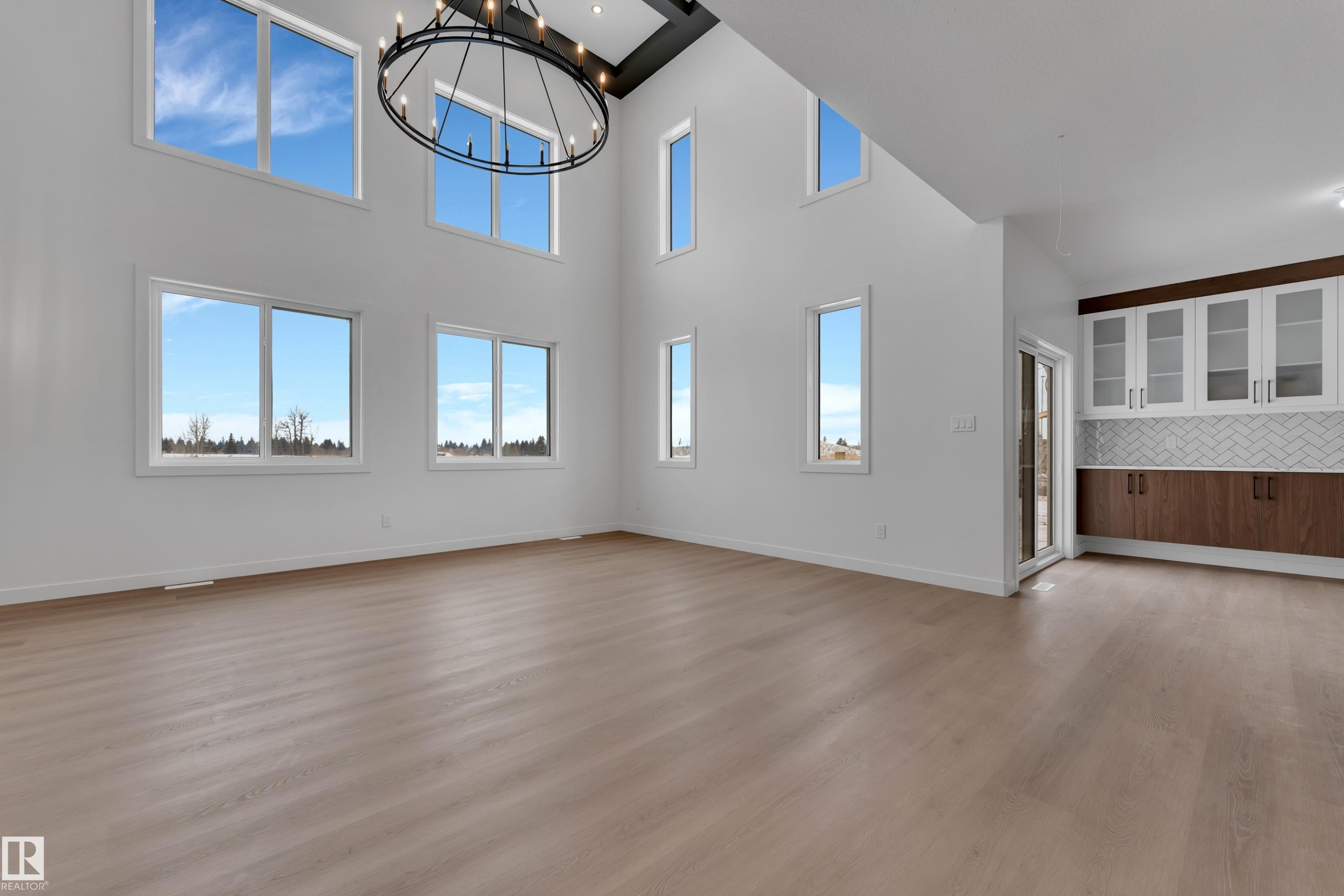 Unfurnished living room featuring hanging lights, light wood-style flooring, plenty of natural light, and a high ceiling - 40 Grayson Green, Stony Plain, AB - Indoor Photo Showing Other Room