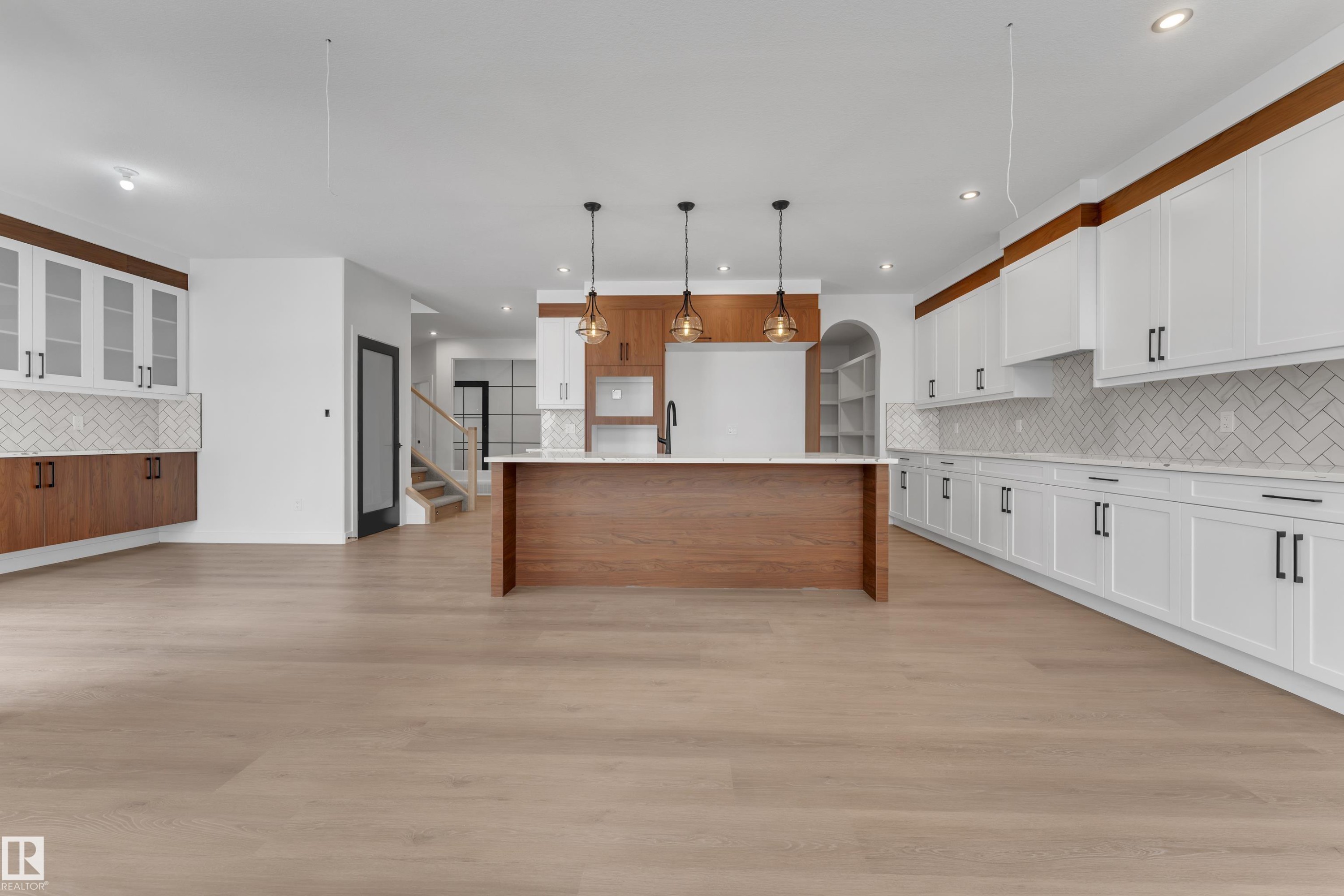 Two tone kitchen with decorative backsplash, pendant lighting, a spacious island, light wood-type flooring, and open floor plan - 40 Grayson Green, Stony Plain, AB - Indoor Photo Showing Kitchen