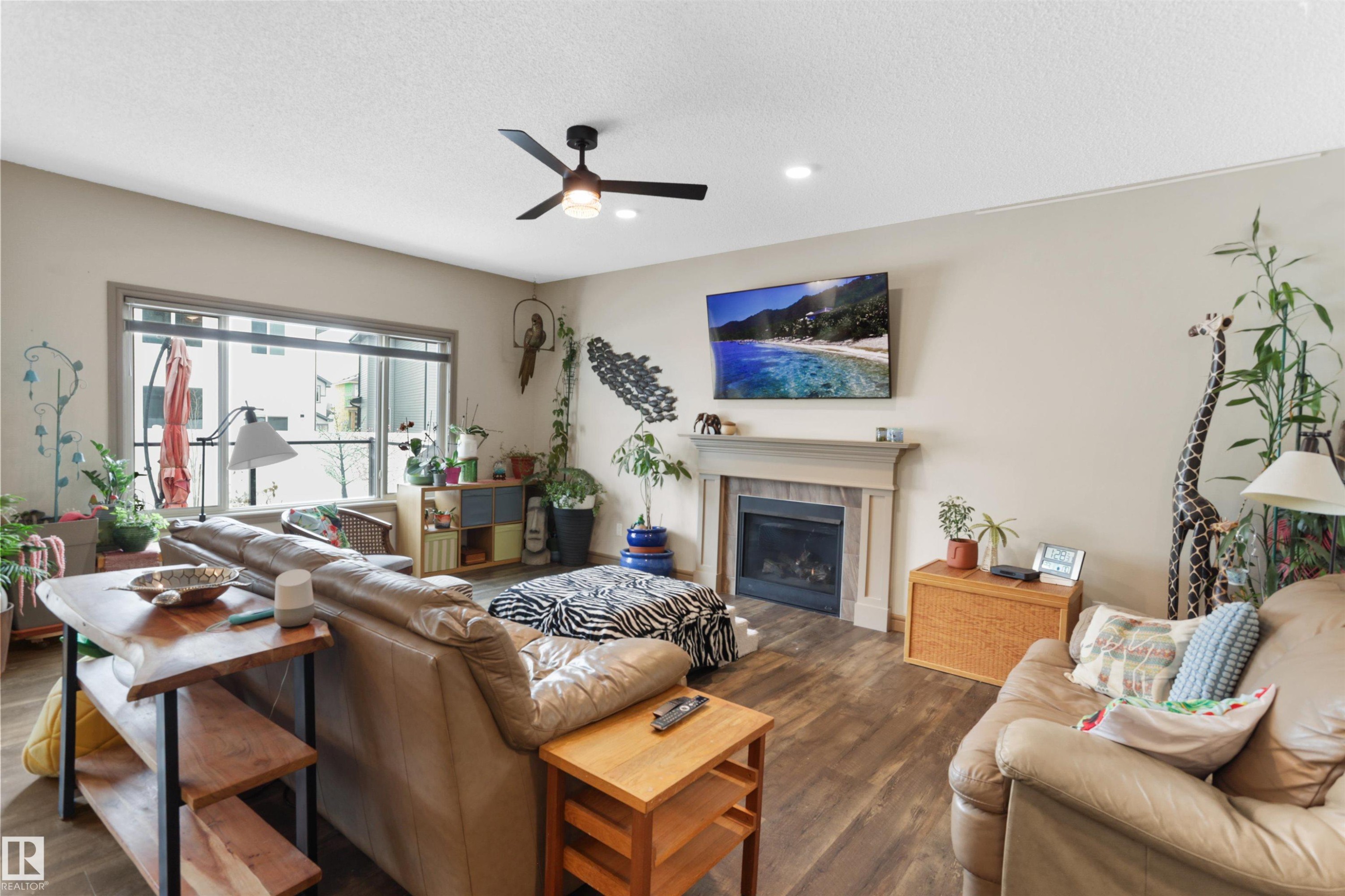 Living room featuring a ceiling fan, dark wood-style floors, a fireplace, a textured ceiling, and recessed lighting - 97 Astoria Point(E), Devon, AB - Indoor Photo Showing Living Room With Fireplace