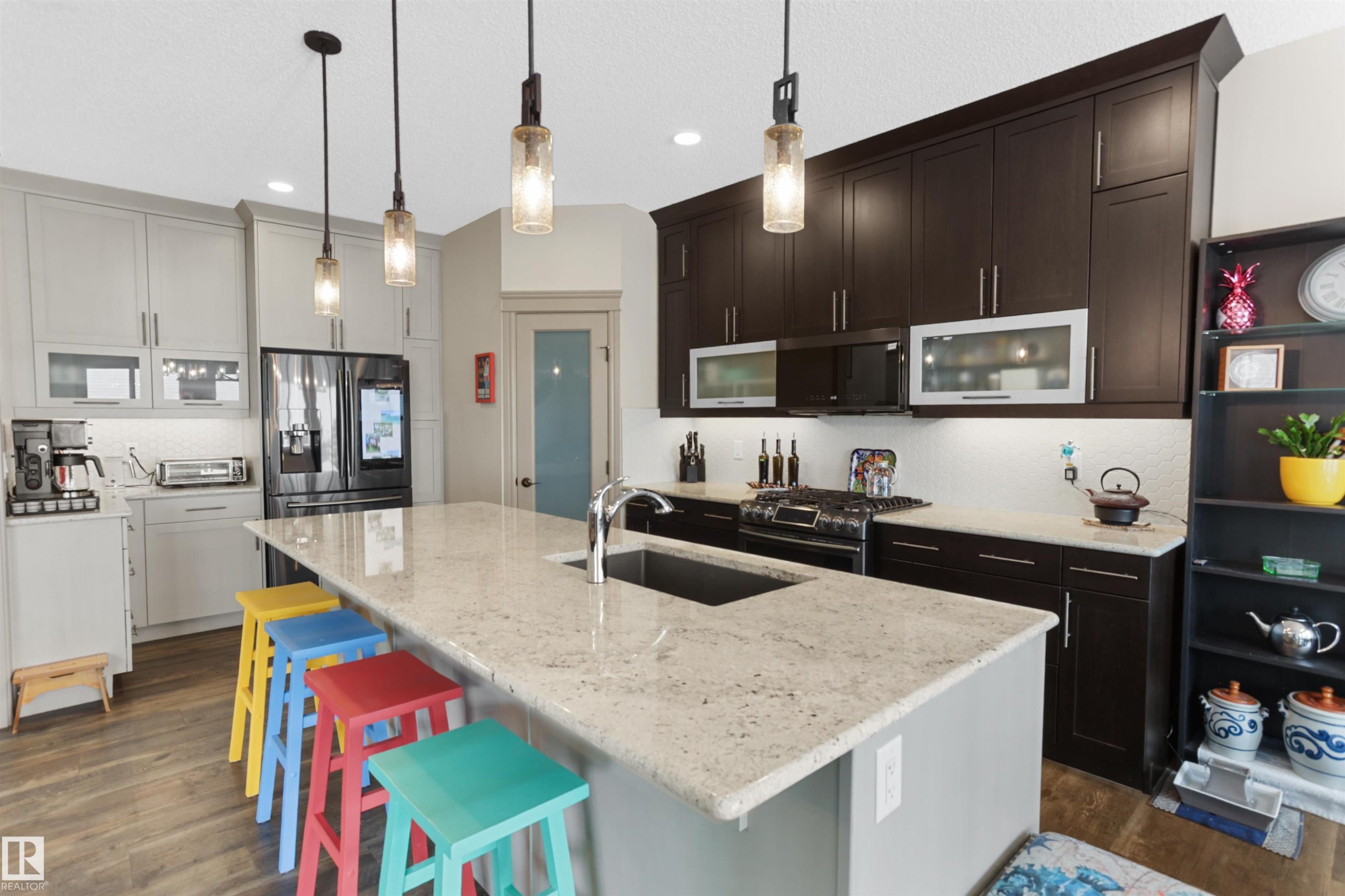 Kitchen featuring decorative light fixtures, stainless steel appliances, light stone counters, and a kitchen island with sink - 97 Astoria Point(E), Devon, AB - Indoor Photo Showing Kitchen With Upgraded Kitchen
