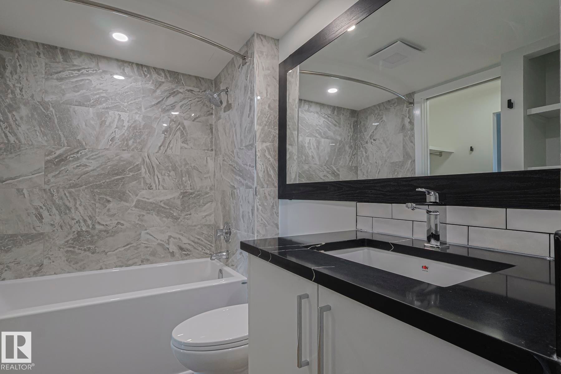 Bathroom featuring tub / shower combination, custom vanity, tile walls, and recessed lighting - 505 10149 Saskatchewan Drive, Edmonton, AB - Indoor Photo Showing Bathroom