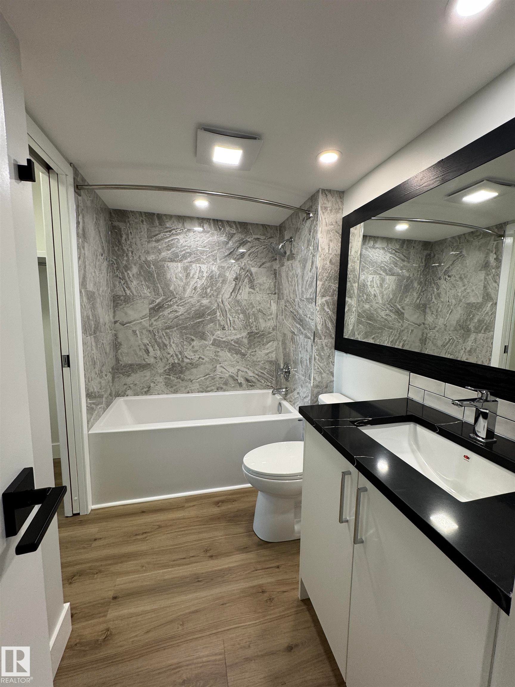 Bathroom with shower / bathtub combination, custom vanity, vinyl plank flooring, and tile walls - 505 10149 Saskatchewan Drive, Edmonton, AB - Indoor Photo Showing Bathroom