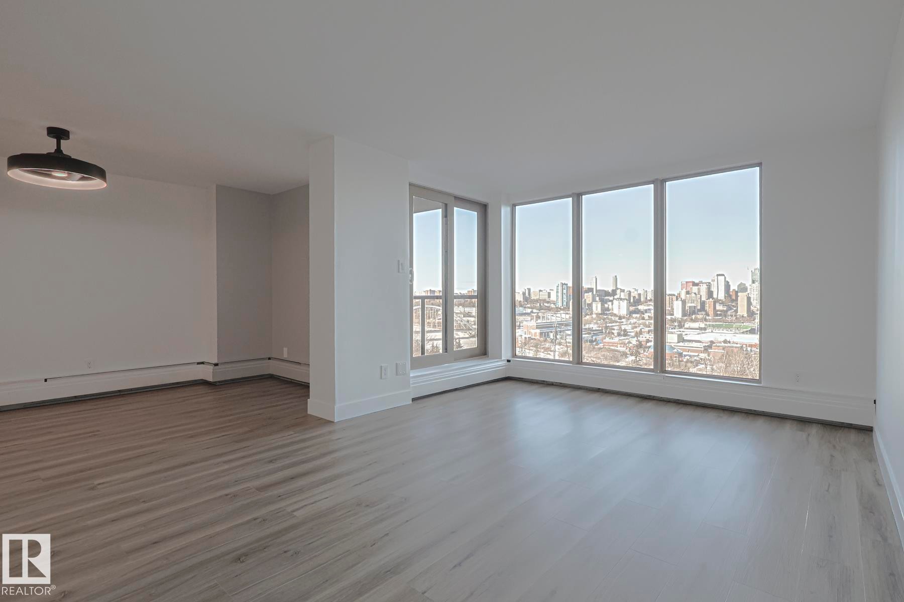 Dining room with a view of skyline, light wood-style vinyl plank flooring, and expansive windows with incredible city skyline view - 505 10149 Saskatchewan Drive, Edmonton, AB - Indoor Photo Showing Other Room
