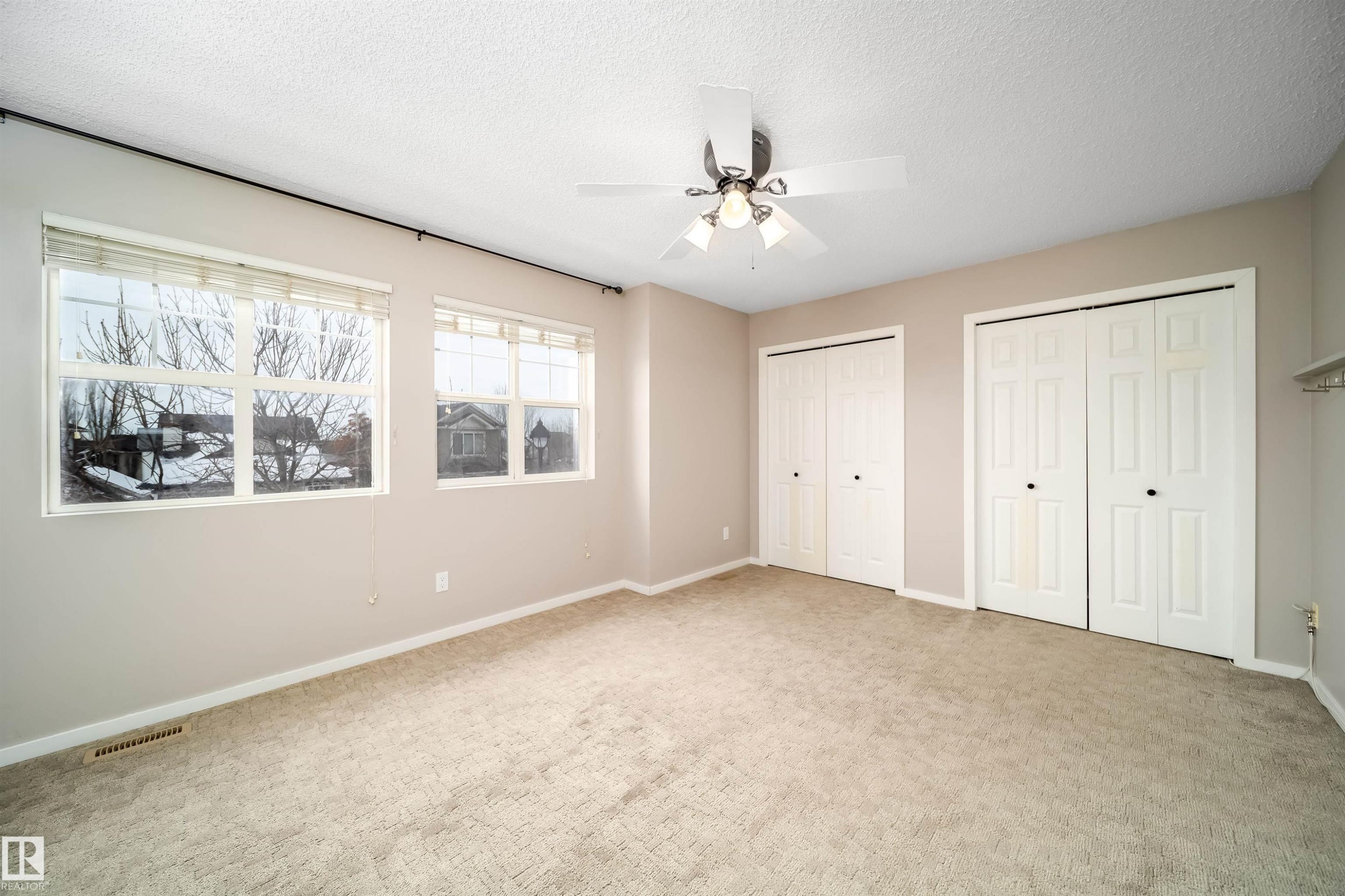 Unfurnished bedroom featuring multiple closets, carpet, a ceiling fan, and a textured ceiling - 1695 Tompkins Place, Edmonton, AB - Indoor Photo Showing Other Room