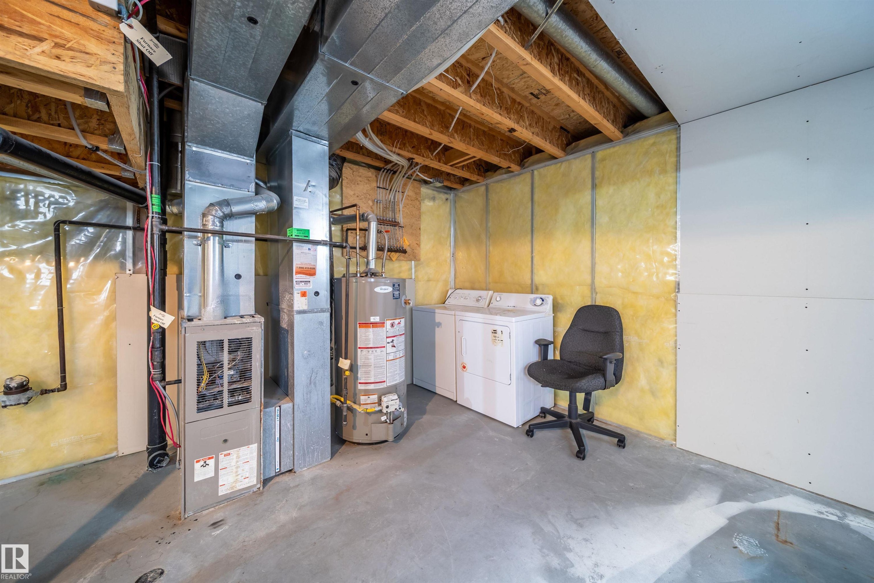 Unfinished basement featuring water heater, washer and clothes dryer, and heating unit - 1695 Tompkins Place, Edmonton, AB - Indoor Photo Showing Basement