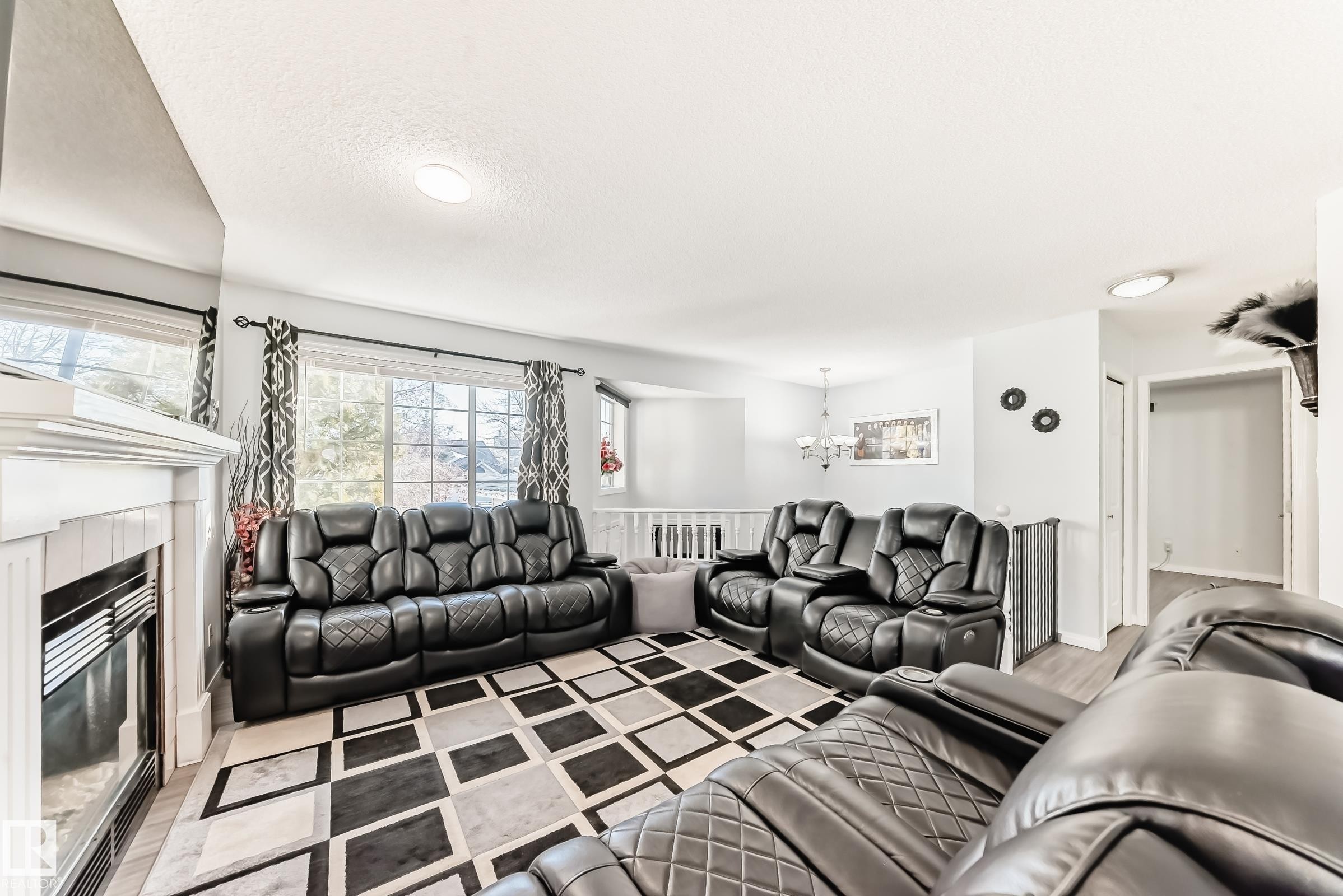 Living area with a fireplace, light wood-style floors, suspended lighting, and a textured ceiling - 6 Jefferson Road, Edmonton, AB - Indoor Photo Showing Living Room
