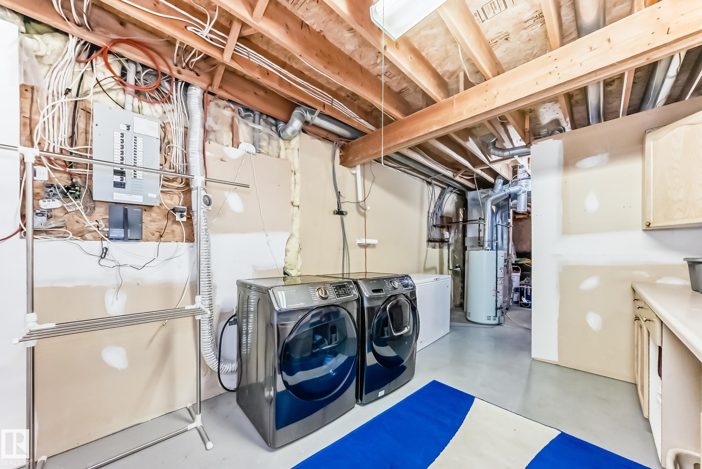 Laundry area featuring finished concrete flooring, separate washer and dryer, electric panel, and gas water heater - 6 Jefferson Road, Edmonton, AB - Indoor Photo Showing Laundry Room