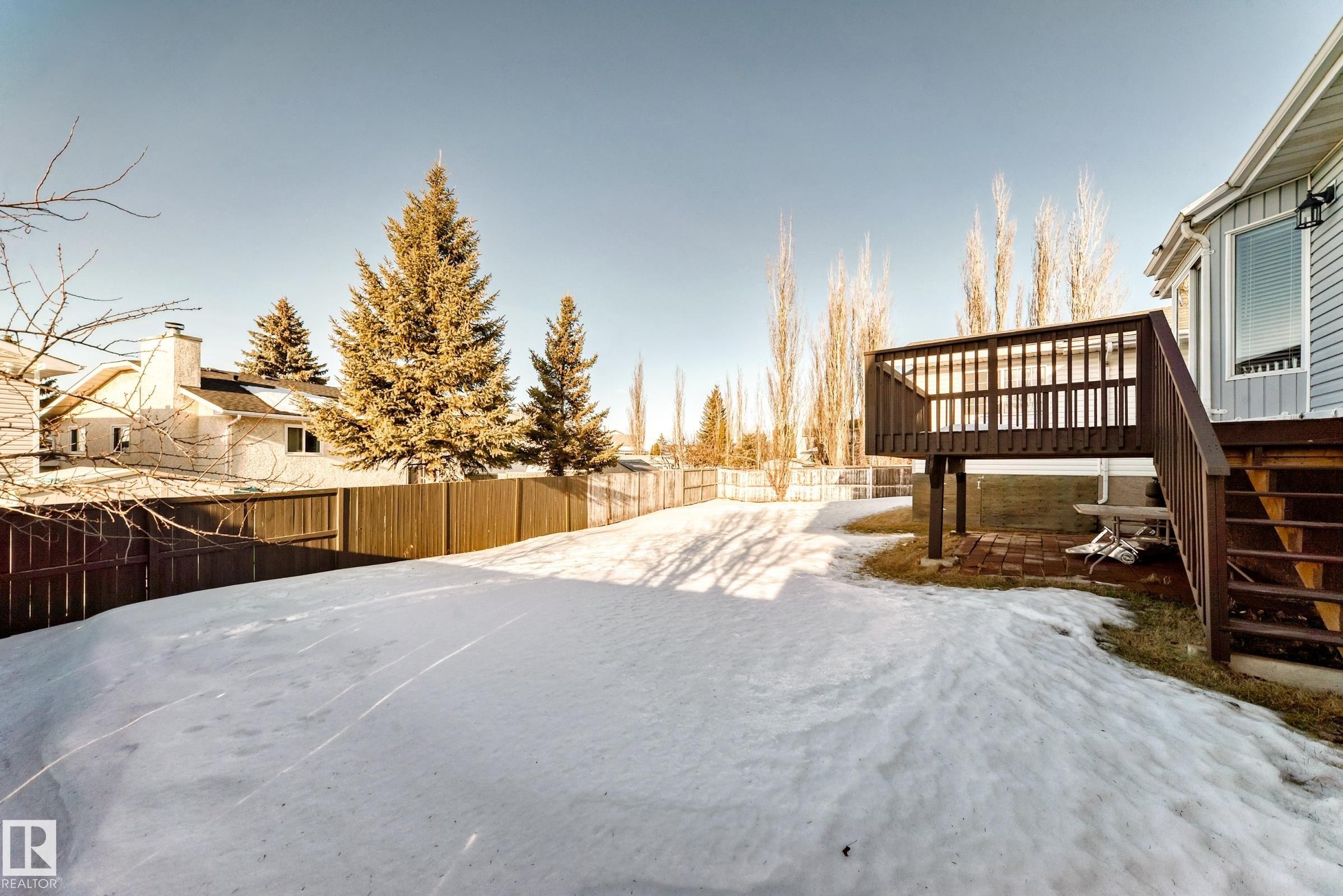 Snowy yard featuring a fenced backyard, a wooden deck, and a patio - 6 Jefferson Road, Edmonton, AB - Outdoor