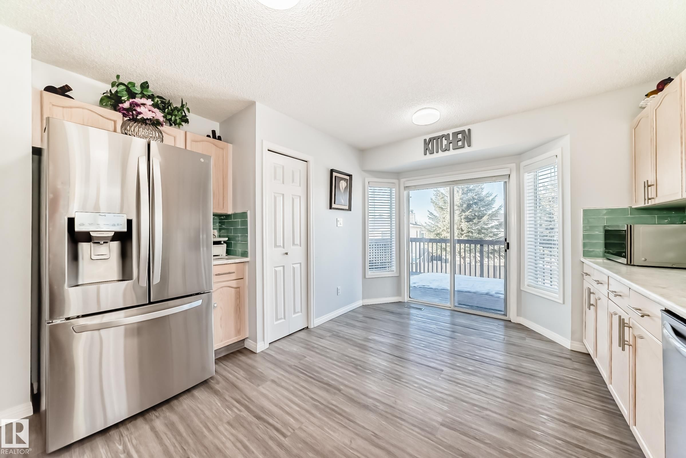 Kitchen with stainless steel appliances, light wood finish cabinetry, backsplash, light wood-type flooring, and a textured ceiling - 6 Jefferson Road, Edmonton, AB - Indoor Photo Showing Kitchen