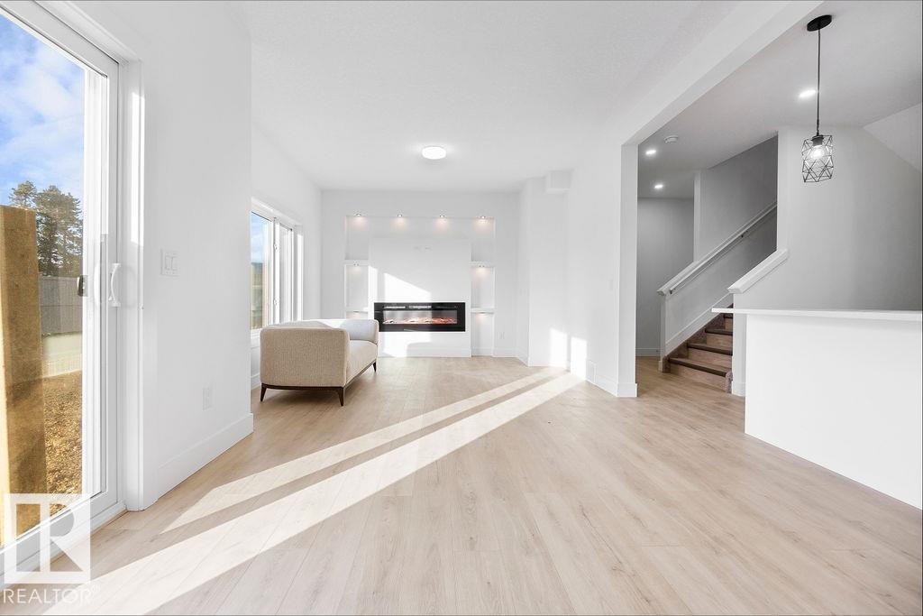 Living area featuring light wood-style floors and a glass covered fireplace - 235 Linden Loop, Leduc, AB - Indoor