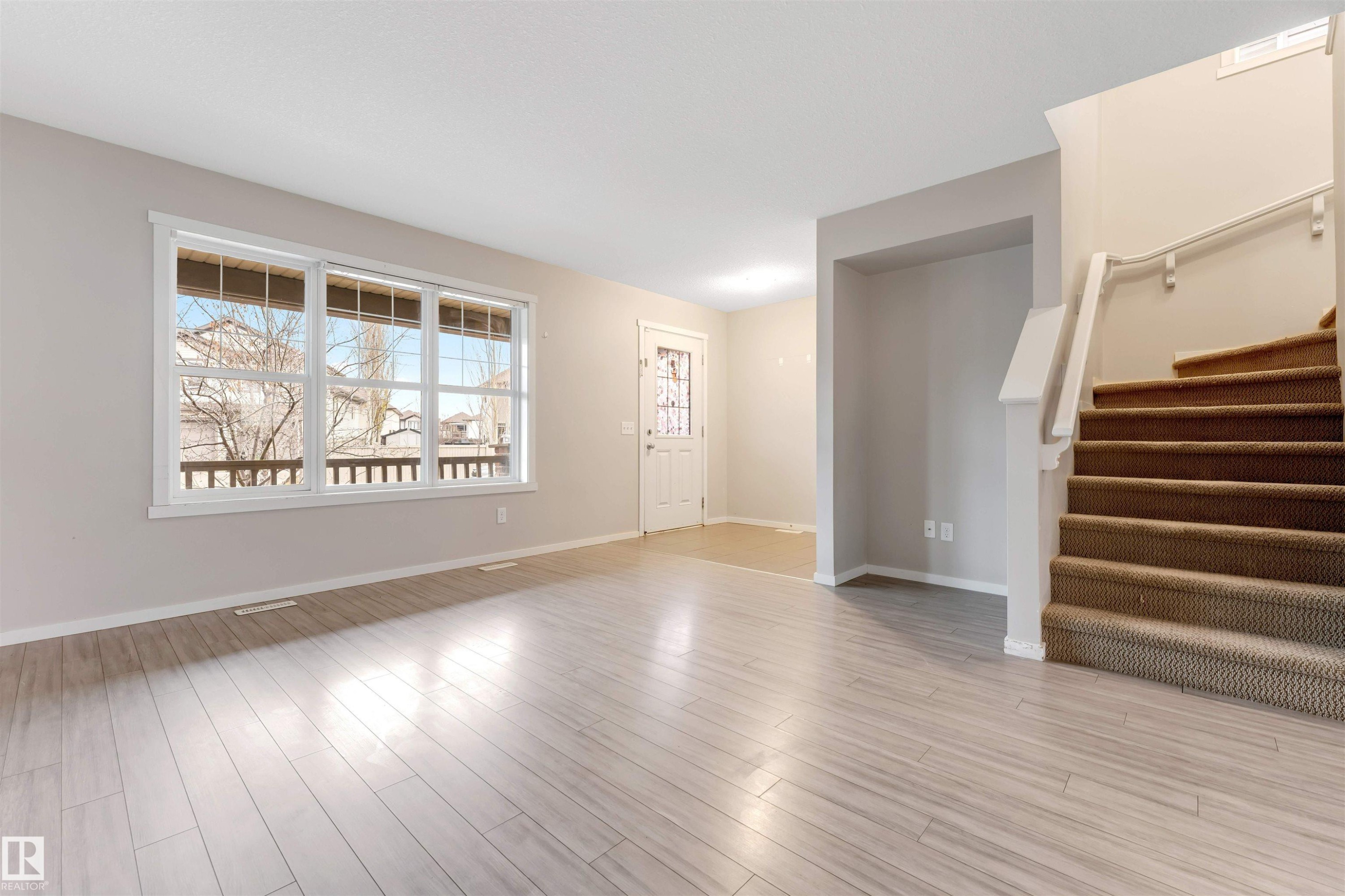 Unfurnished living room with stairway and light wood-type flooring - 610 Tamarack Road, Edmonton, AB - Indoor Photo Showing Other Room