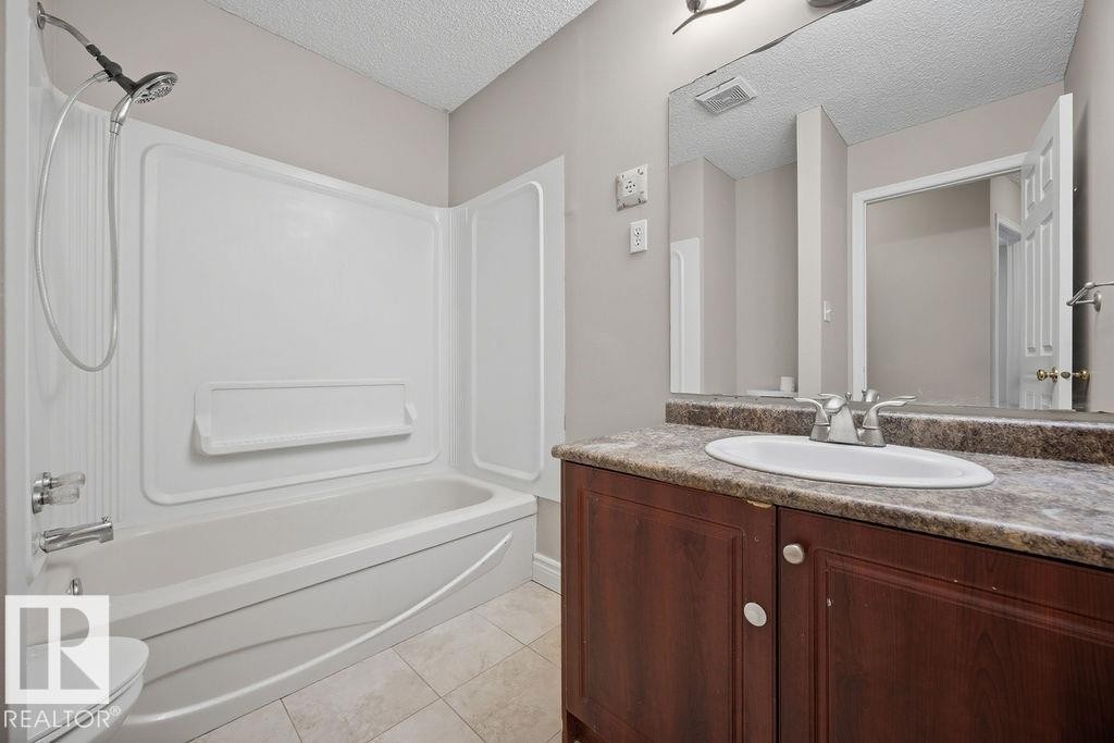 Bathroom with a textured ceiling, vanity, light tile patterned floors, and shower / bathtub combination - 736 Johns Road, Edmonton, AB - Indoor Photo Showing Bathroom