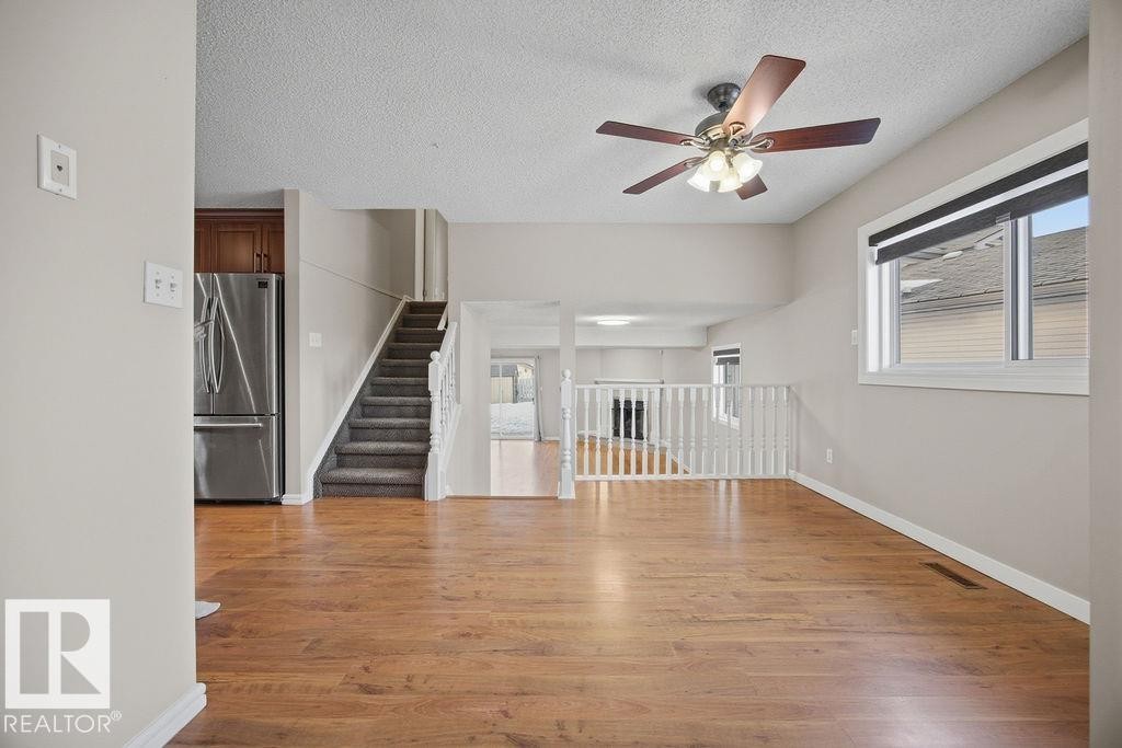 Unfurnished living room featuring light wood finished floors, healthy amount of natural light, a textured ceiling, and ceiling fan - 736 Johns Road, Edmonton, AB - Indoor Photo Showing Other Room