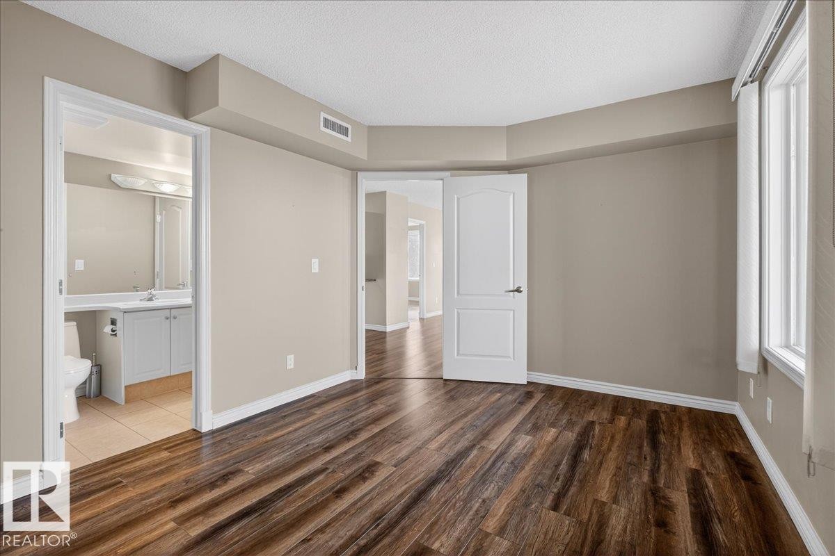 Unfurnished bedroom featuring dark wood-type flooring and a textured ceiling - 402 10649 Saskatchewan Drive, Edmonton, AB - Indoor Photo Showing Other Room
