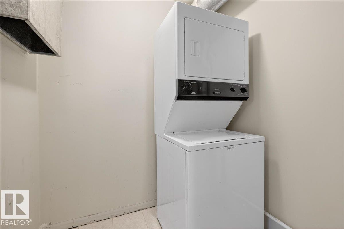 Laundry area featuring stacked washer / drying machine and baseboards - 402 10649 Saskatchewan Drive, Edmonton, AB - Indoor Photo Showing Laundry Room