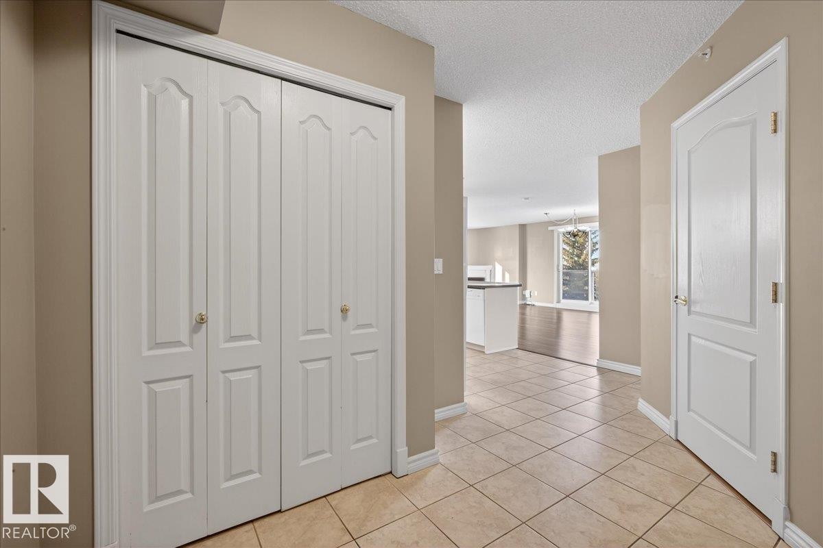 Hall featuring a textured ceiling and light tile patterned floors - 402 10649 Saskatchewan Drive, Edmonton, AB - Indoor Photo Showing Other Room