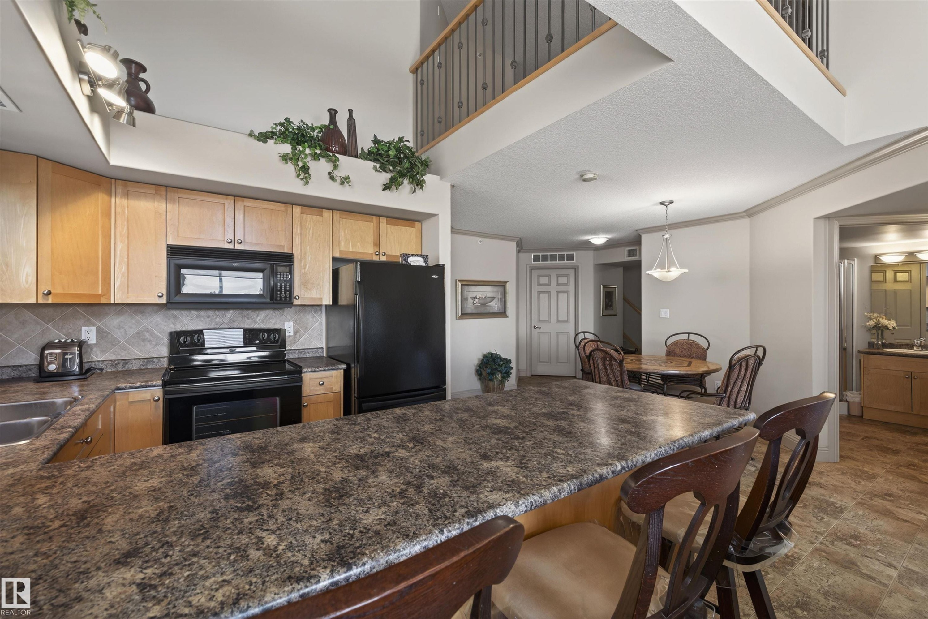 Kitchen featuring black appliances, ornamental molding, backsplash, a textured ceiling, and a peninsula - 427 13005 140 Avenue, Edmonton, AB - Indoor Photo Showing Kitchen