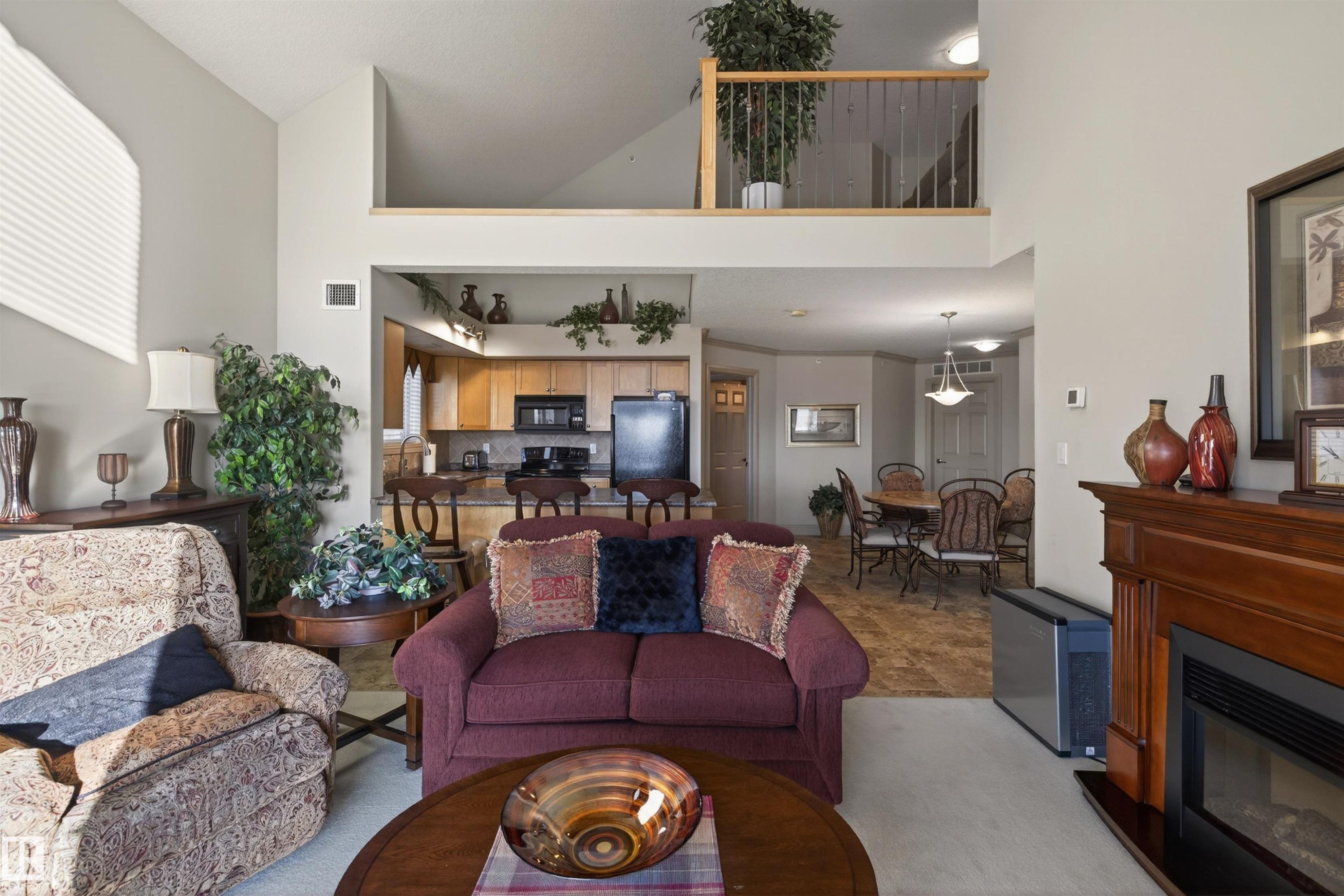 Living room featuring a glass covered fireplace and a high ceiling - 427 13005 140 Avenue, Edmonton, AB - Indoor Photo Showing Living Room With Fireplace