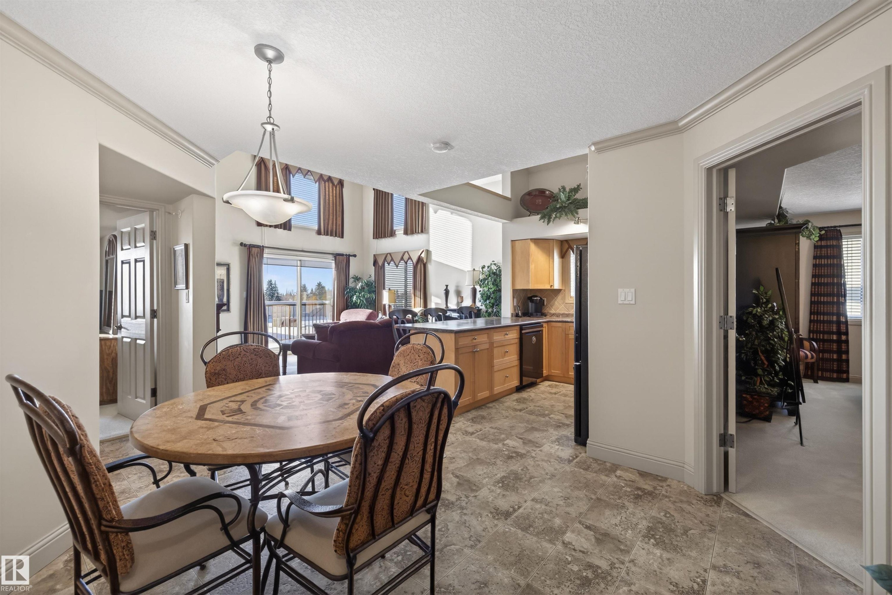 Dining area featuring a textured ceiling, ornamental molding, and stone finish floors - 427 13005 140 Avenue, Edmonton, AB - Indoor Photo Showing Dining Room