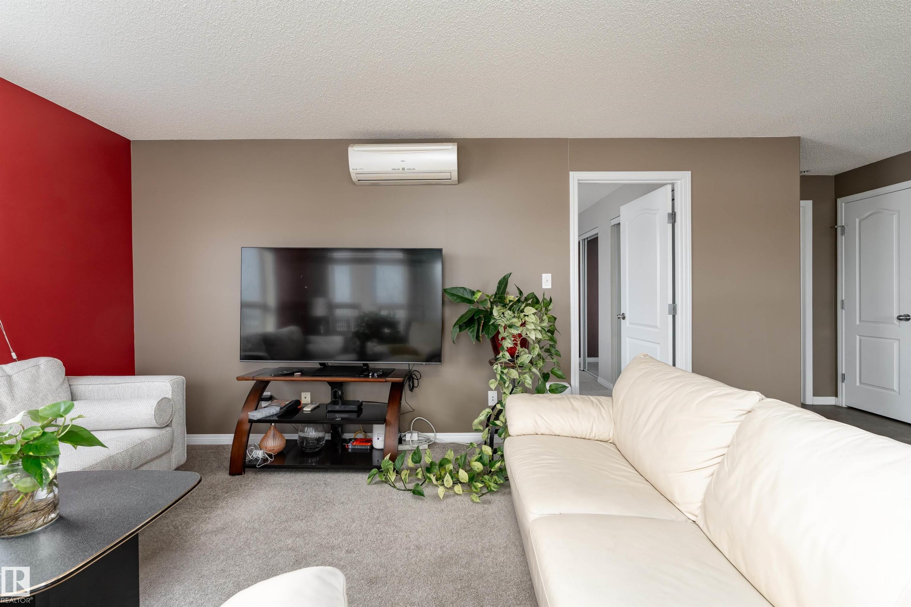 Living area featuring carpet floors, a wall mounted mini split, and a textured ceiling - 325 1520 Hammond Gate, Edmonton, AB - Indoor Photo Showing Other Room