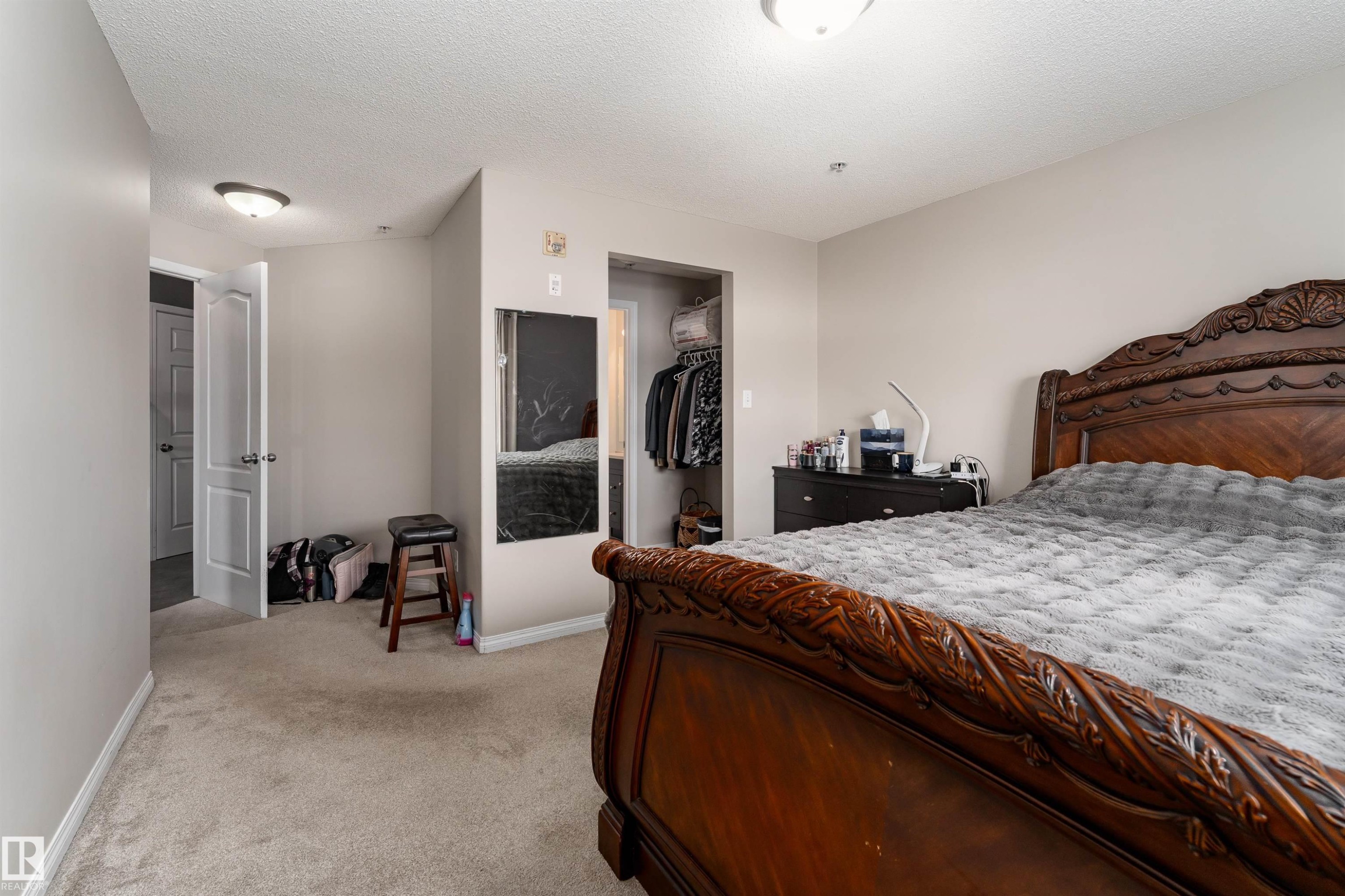 Bedroom with light colored carpet, a spacious closet, and a textured ceiling - 325 1520 Hammond Gate, Edmonton, AB - Indoor Photo Showing Bedroom
