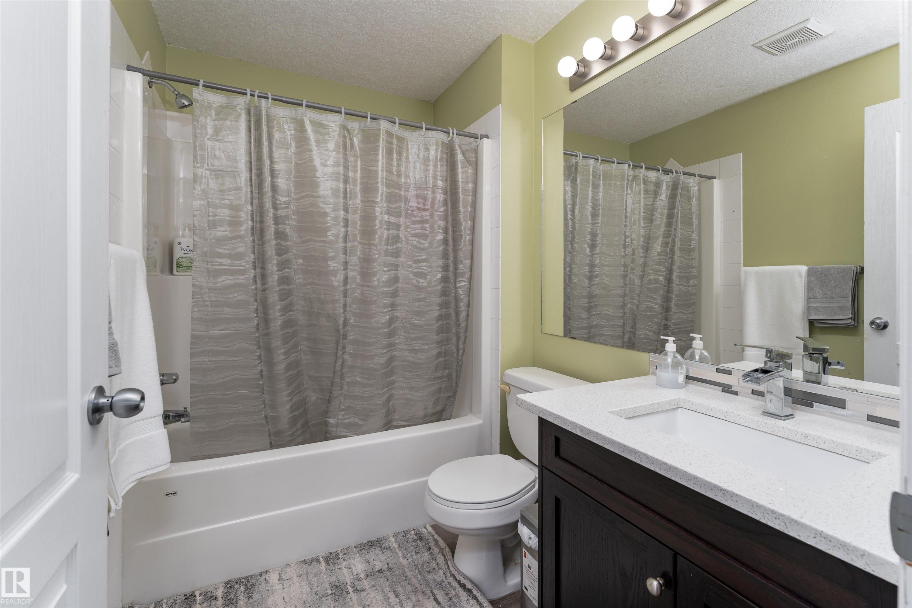 Full bathroom featuring a textured ceiling, vanity, and shower / bath combo - 325 1520 Hammond Gate, Edmonton, AB - Indoor Photo Showing Bathroom