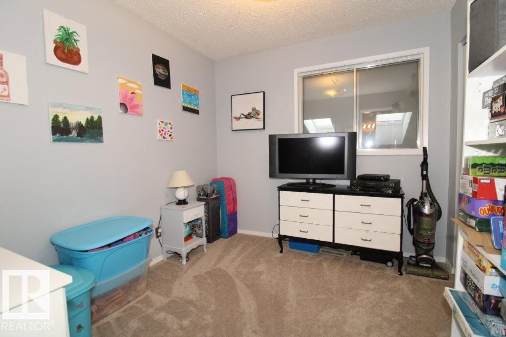 Recreation room featuring a textured ceiling and light colored carpet - 2812 35 Street Nw, Edmonton, AB - Indoor