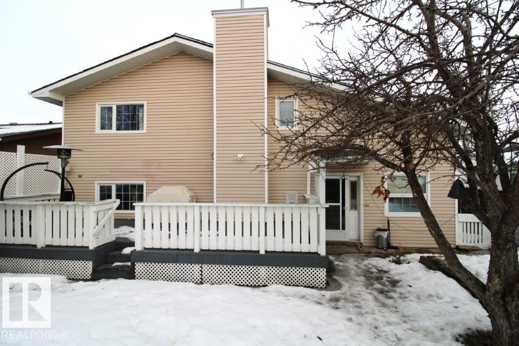 Snow covered rear of property featuring a wooden deck and a chimney - 2812 35 Street Nw, Edmonton, AB - Outdoor With Deck Patio Veranda