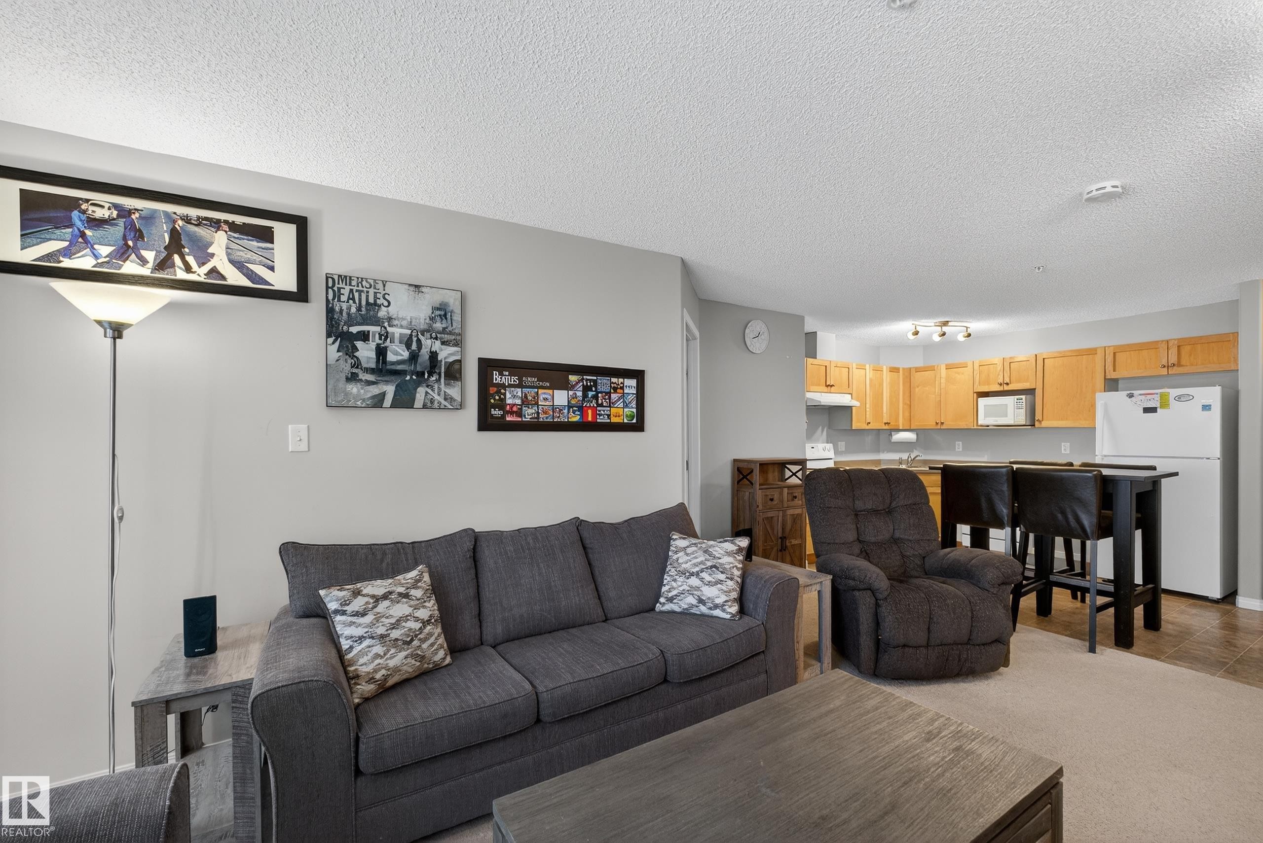 Carpeted living room featuring a textured ceiling - 131 1520 Hammond Gate, Edmonton, AB - Indoor Photo Showing Living Room