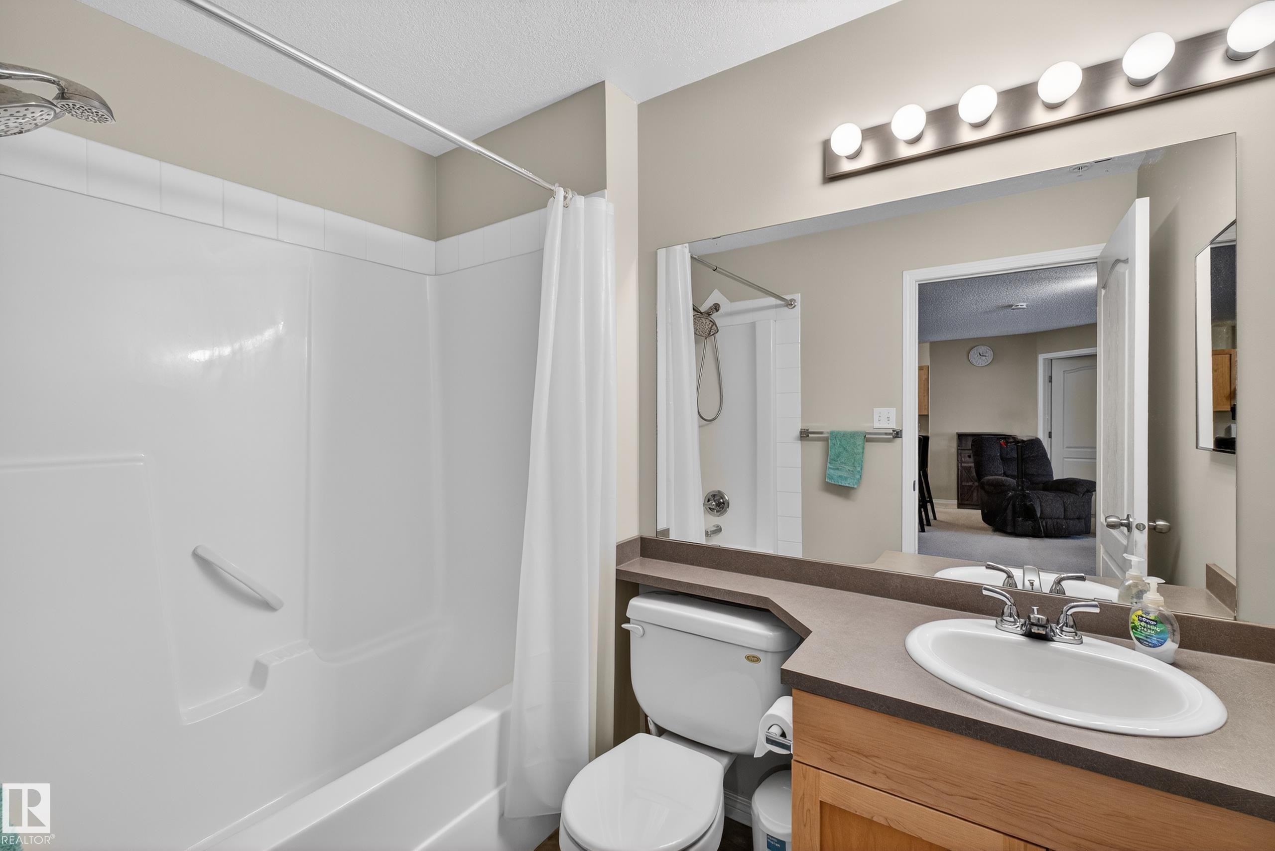 Bathroom with vanity, shower / tub combo, and a textured ceiling - 131 1520 Hammond Gate, Edmonton, AB - Indoor Photo Showing Bathroom