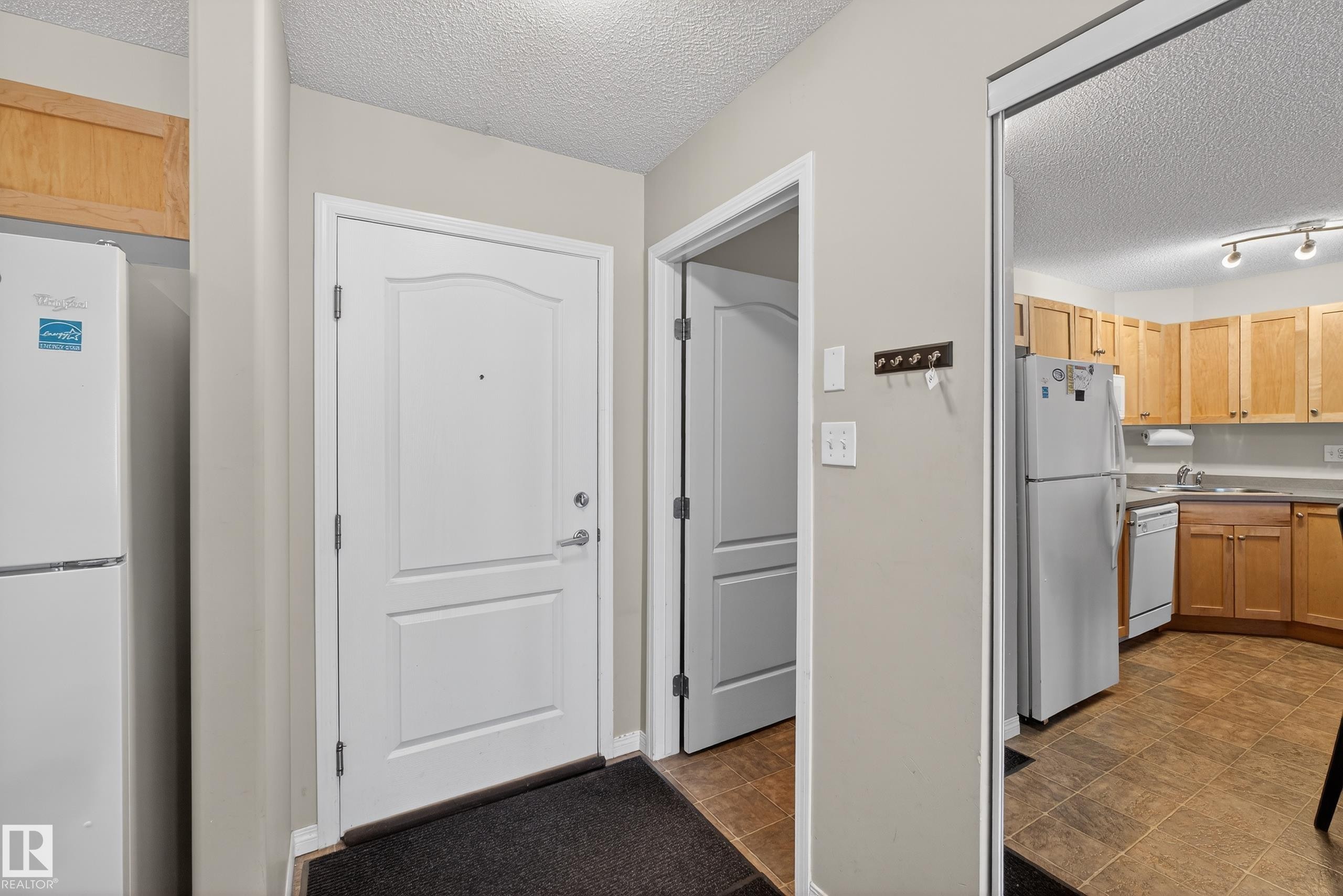 Kitchen with a textured ceiling, white appliances, and light countertops - 131 1520 Hammond Gate, Edmonton, AB - Indoor Photo Showing Kitchen