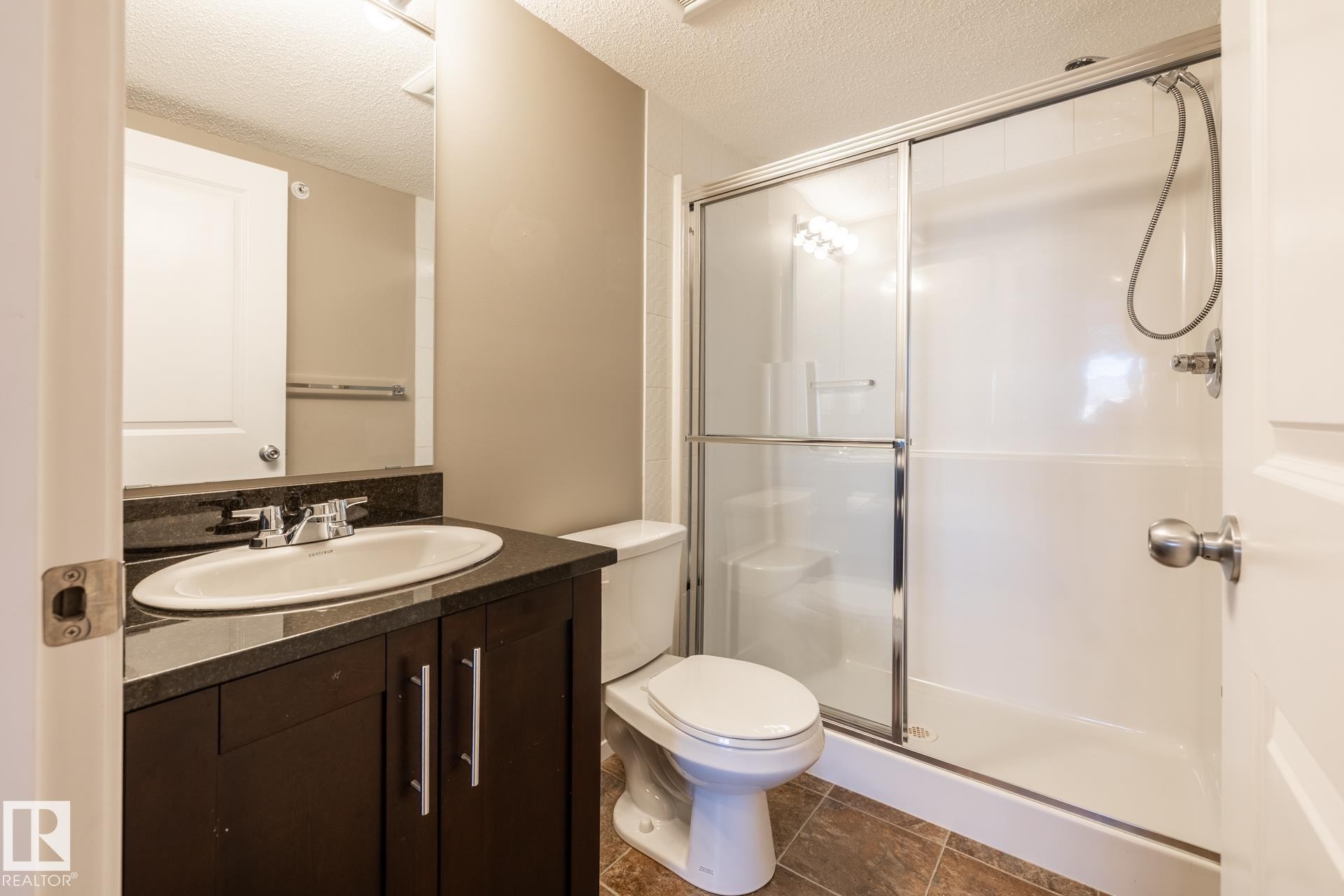 Full bathroom with a textured ceiling, a shower stall, and vanity - 433 3315 James Mowatt Trail, Edmonton, AB - Indoor Photo Showing Bathroom