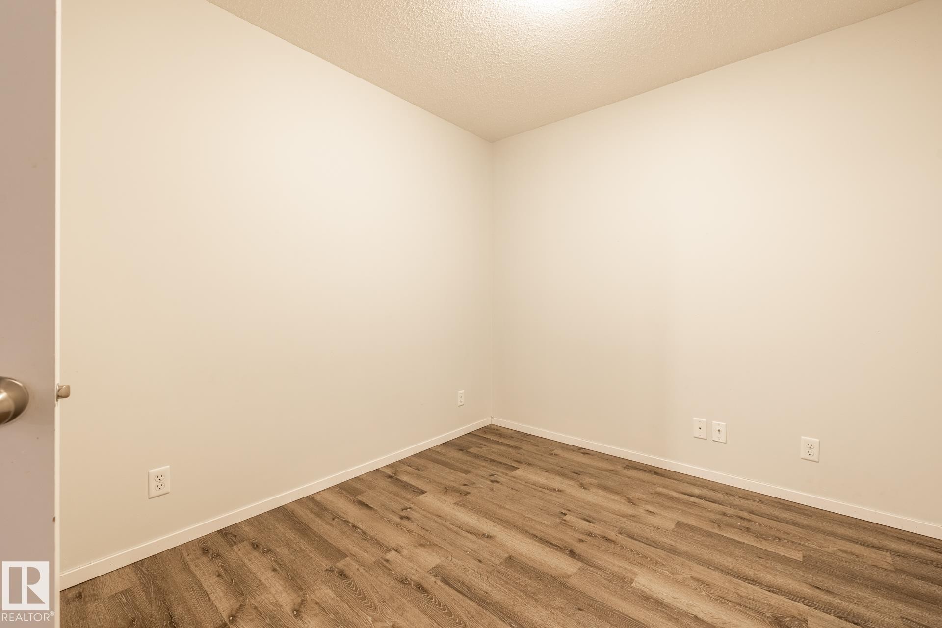 Unfurnished room with a textured ceiling and wood finished floors - 433 3315 James Mowatt Trail, Edmonton, AB - Indoor Photo Showing Other Room