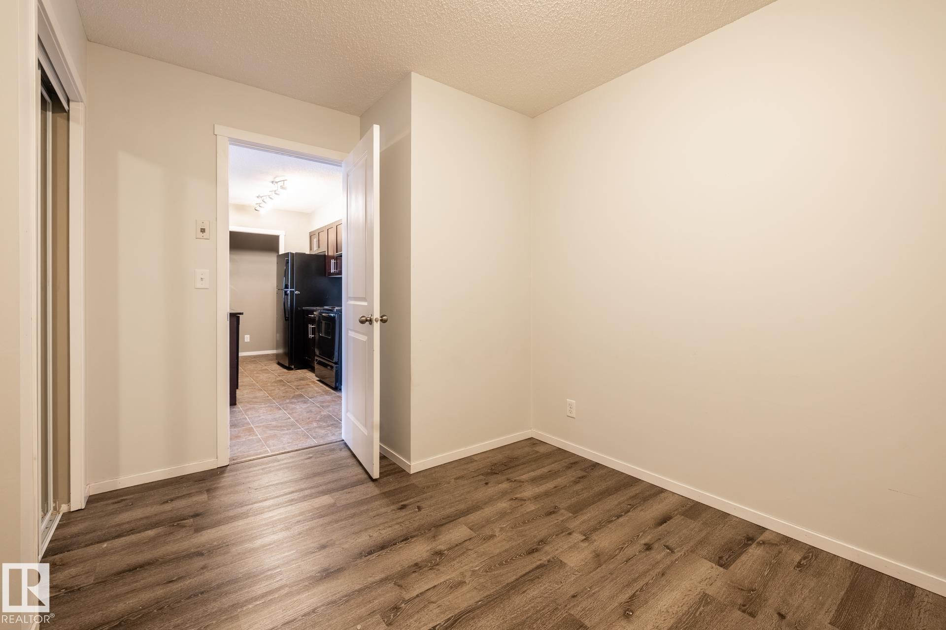 Unfurnished bedroom with a textured ceiling and dark wood-style flooring - 433 3315 James Mowatt Trail, Edmonton, AB - Indoor Photo Showing Other Room