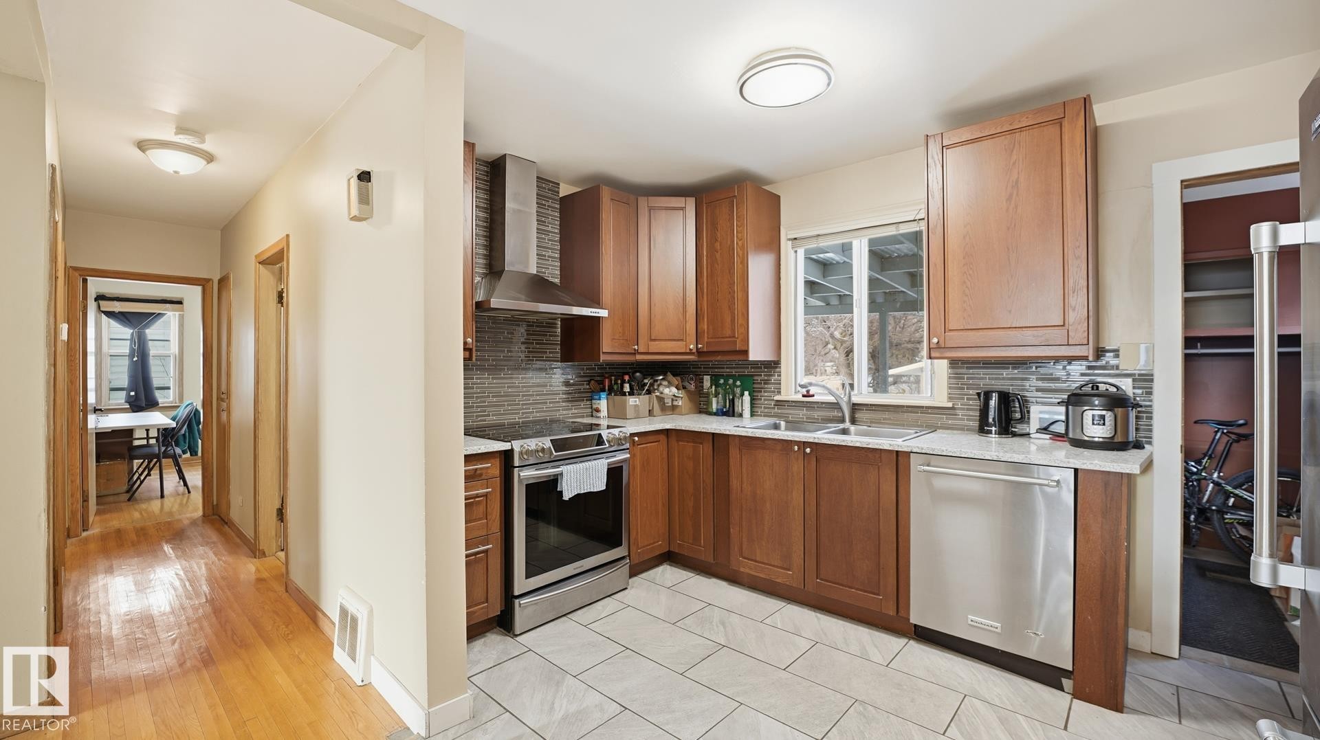 Kitchen featuring stainless steel appliances, wood finish cabinetry, backsplash, and light stone counters - 11520 78 Avenue Nw, Edmonton, AB - Indoor Photo Showing Kitchen With Double Sink