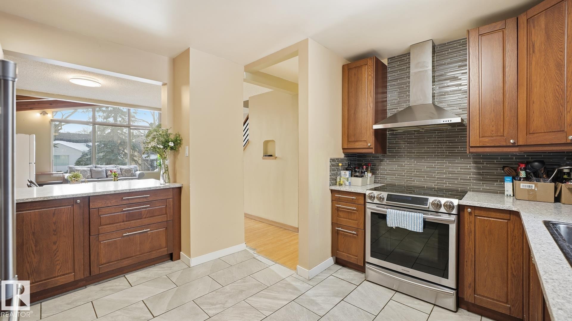 Kitchen featuring stainless steel electric stove, light stone counters, wood finish cabinetry, backsplash, and light tile patterned flooring - 11520 78 Avenue Nw, Edmonton, AB - Indoor Photo Showing Kitchen