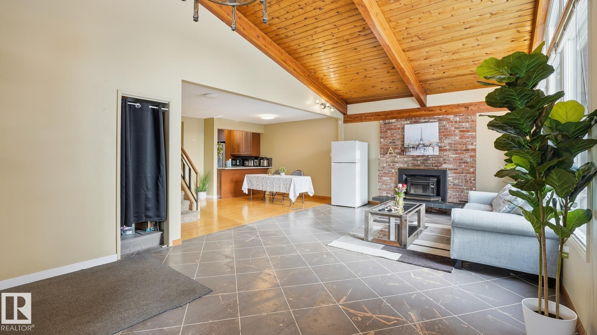 Living area featuring a high wood beamed ceiling and a brick fireplace - 11520 78 Avenue Nw, Edmonton, AB - Indoor With Fireplace