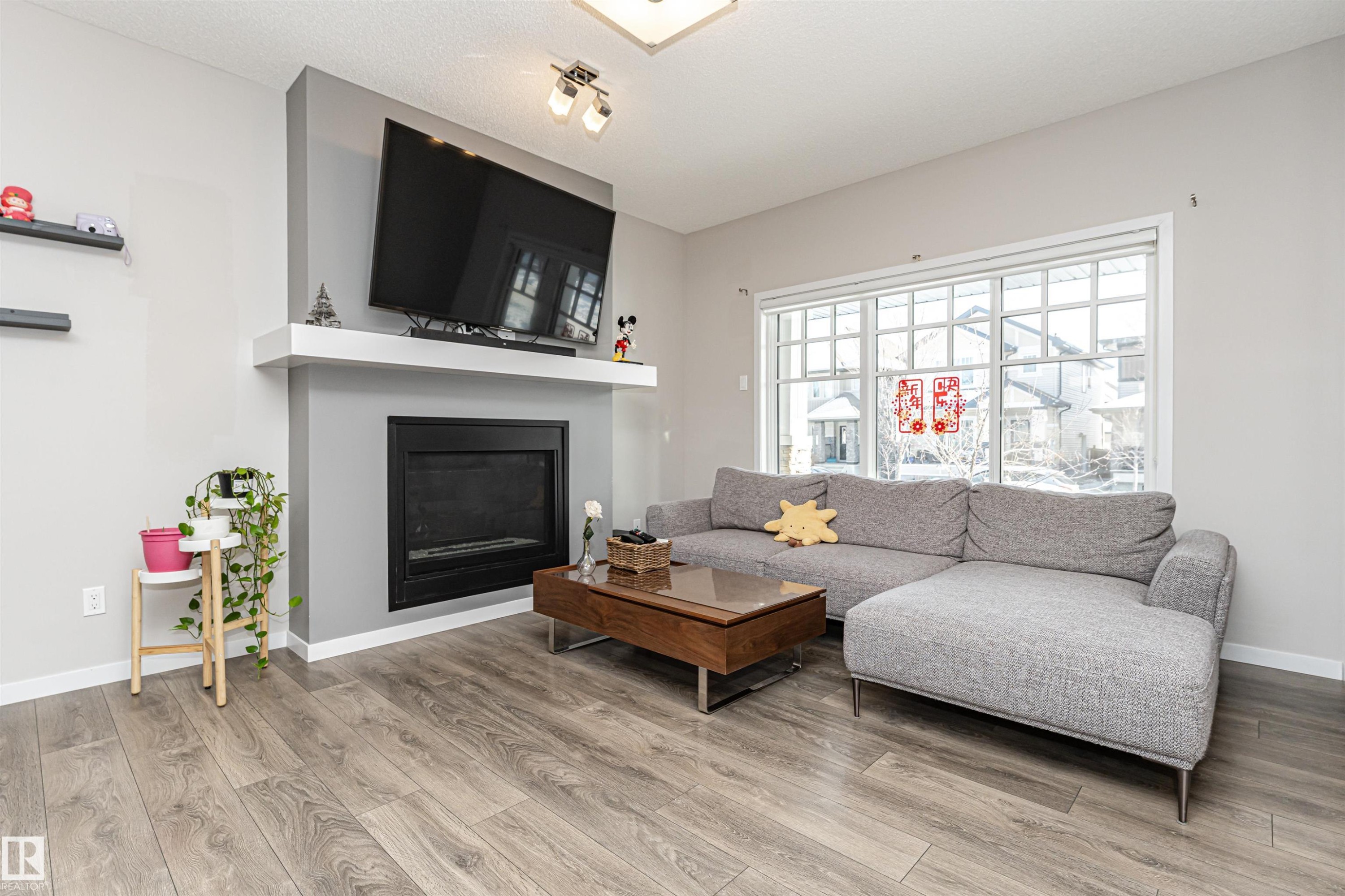 Living room with a glass covered fireplace and wood finished floors - 4008 Allan Crescent, Edmonton, AB - Indoor Photo Showing Living Room With Fireplace