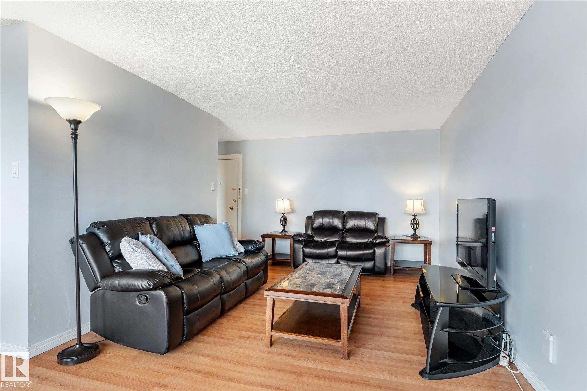 Living room with light wood-style flooring and a textured ceiling - 304 9725 106 Street, Edmonton, AB - Indoor Photo Showing Living Room