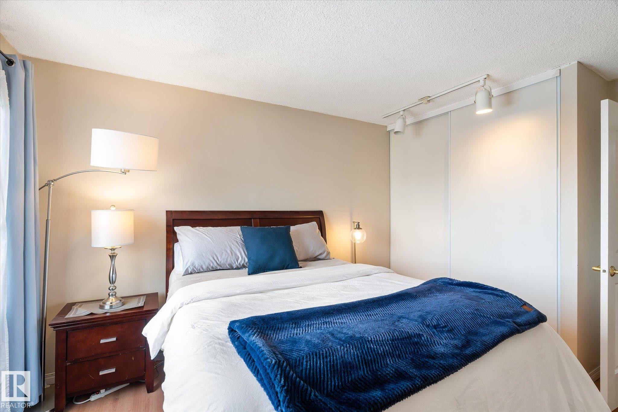 Bedroom featuring track lighting, a closet, a textured ceiling, and wood finished floors - 304 9725 106 Street, Edmonton, AB - Indoor Photo Showing Bedroom
