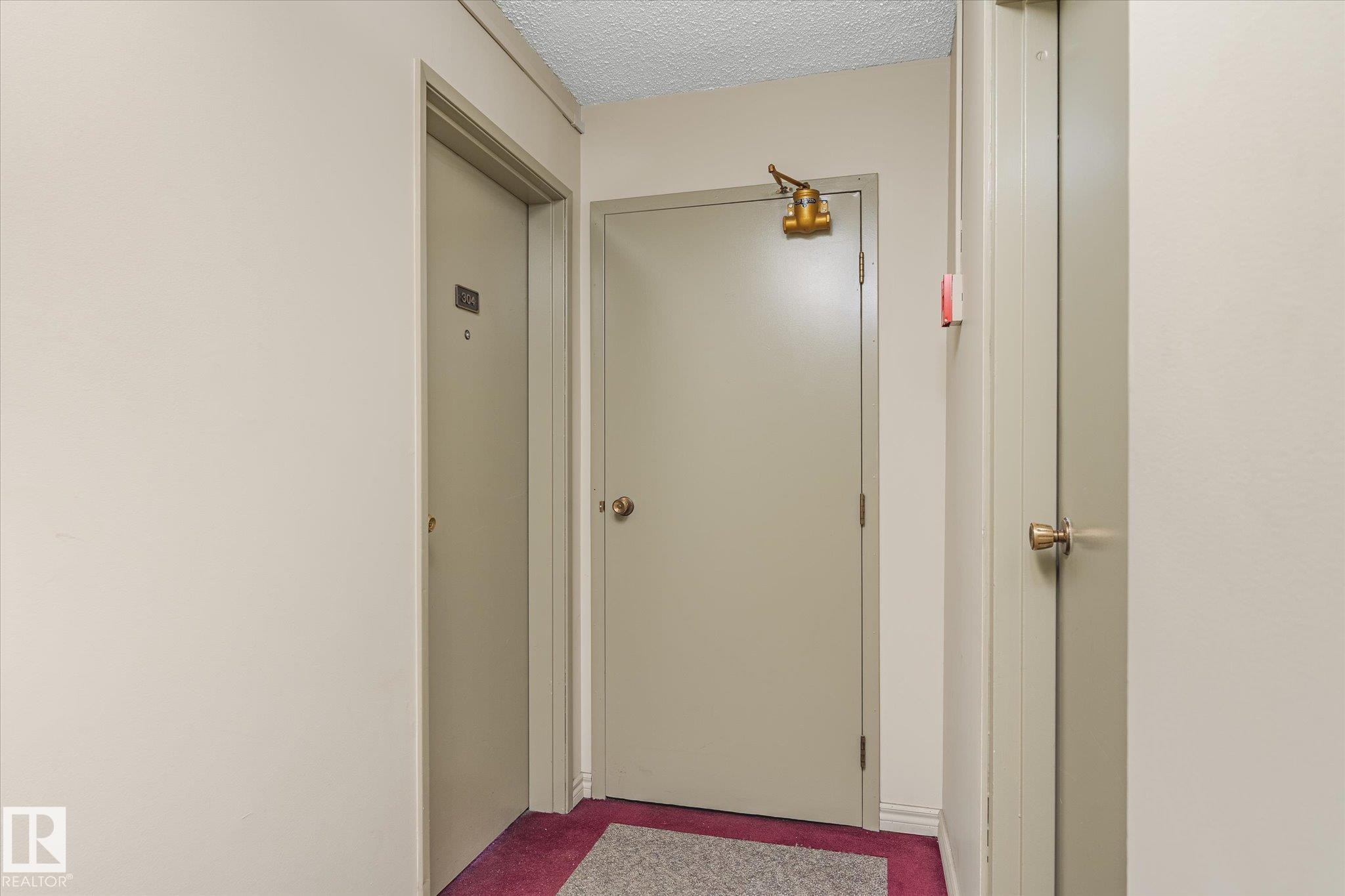 Corridor featuring a textured ceiling and carpet floors - 304 9725 106 Street, Edmonton, AB - Indoor Photo Showing Other Room