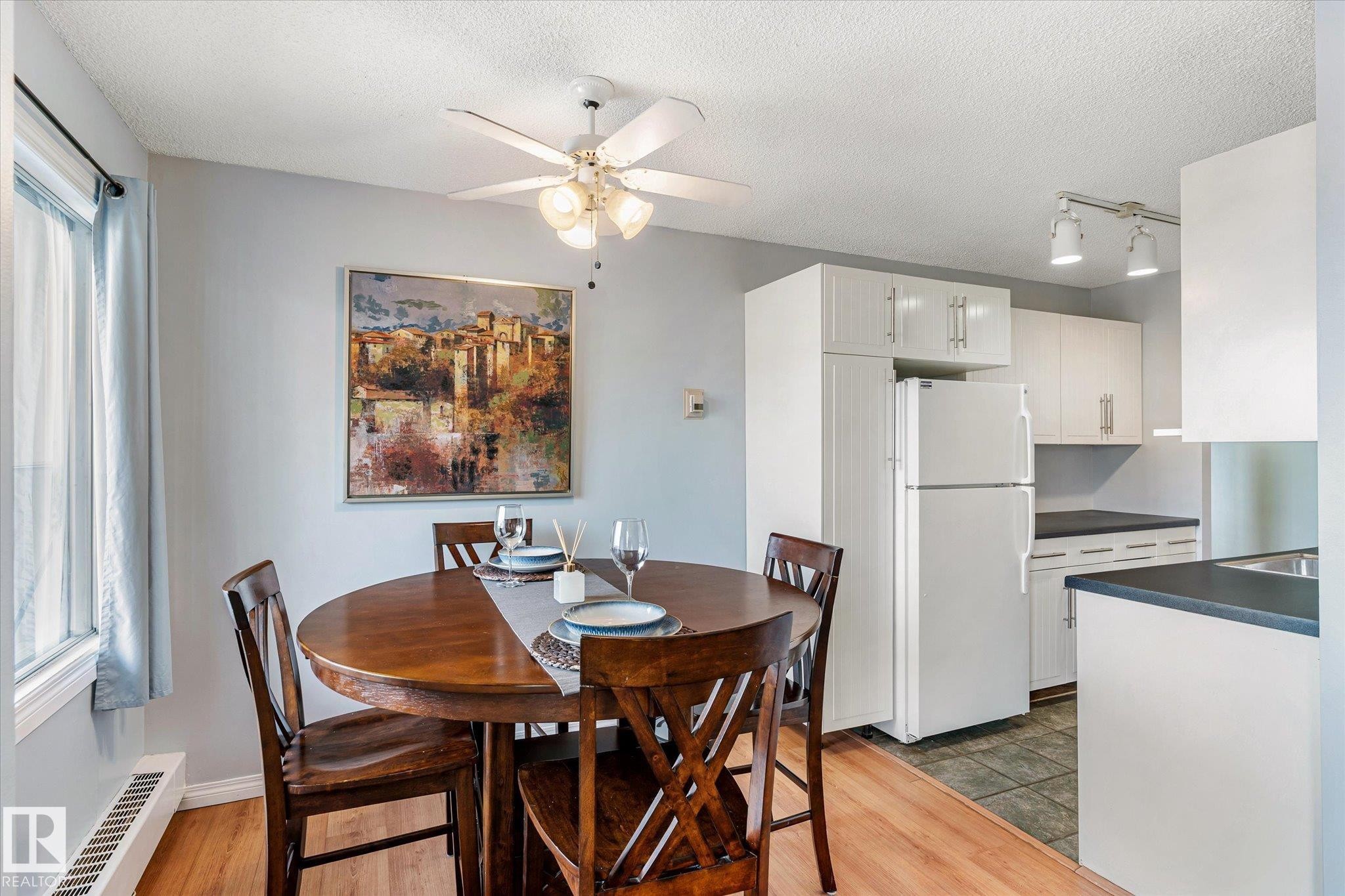 Dining room featuring light wood-style floors, a textured ceiling, a ceiling fan, and track lighting - 304 9725 106 Street, Edmonton, AB - Indoor Photo Showing Dining Room